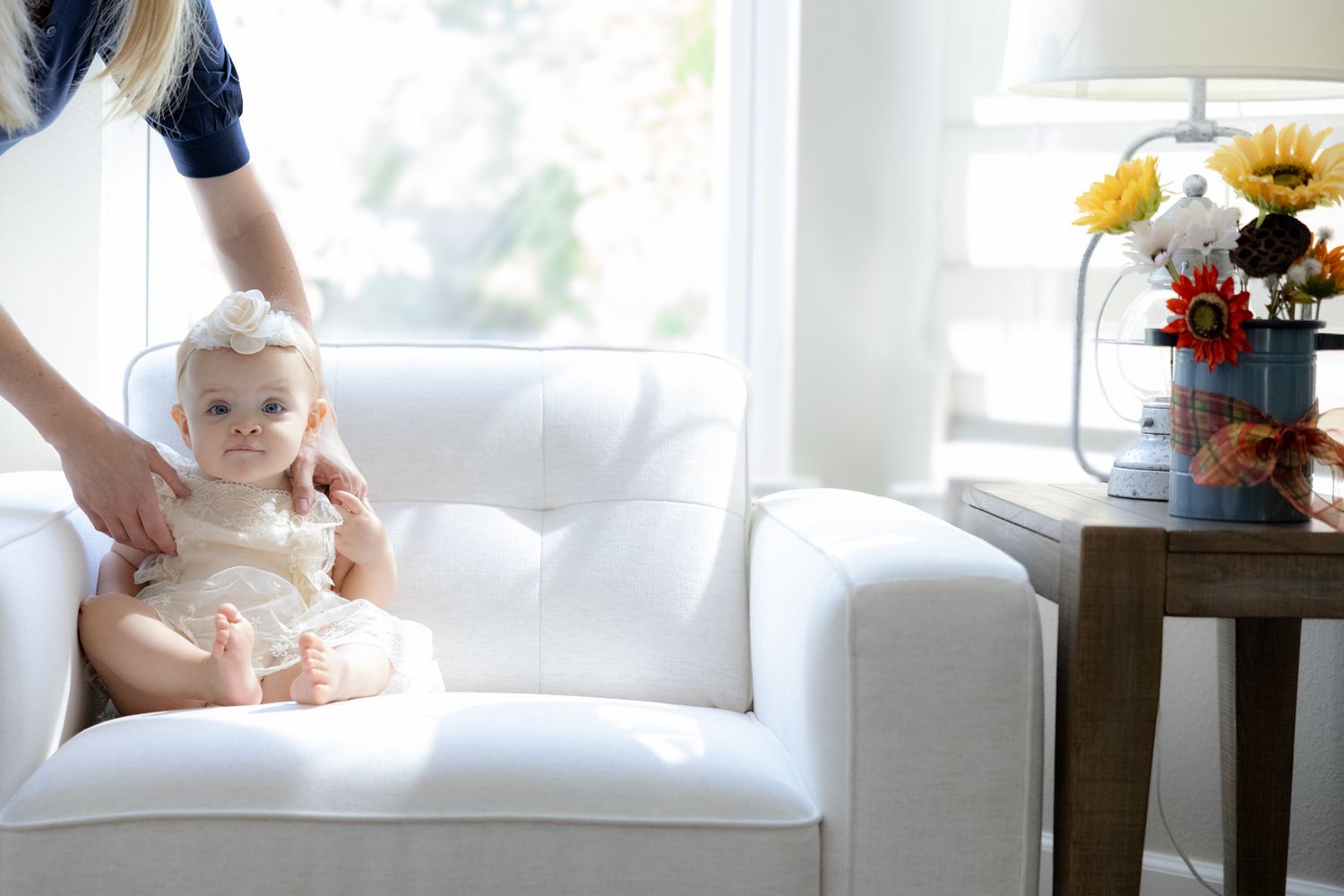 Four connected photos show someone sitting on a white couch holding a baby while sunlight streams through nearby windows.