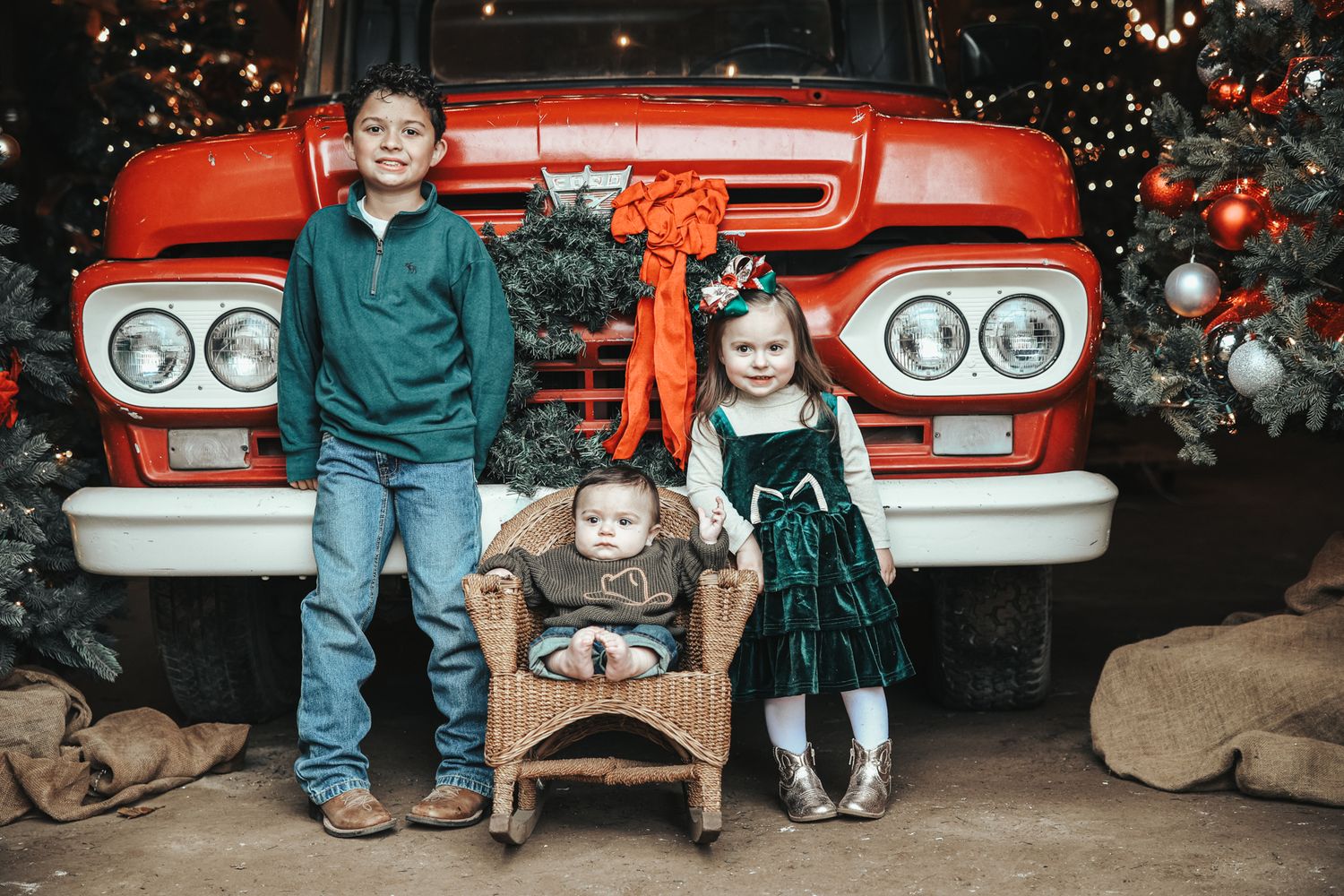 Holiday photo setup with vintage red truck, Christmas decor, rocking chair and festive decorations.