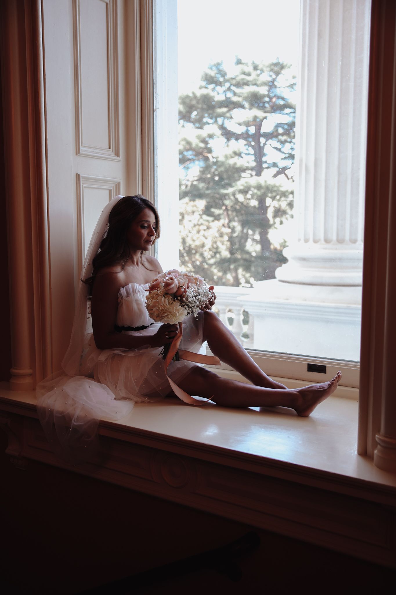 A person lying on a windowsill in a dreamy pose as sunlight streams through the windows.