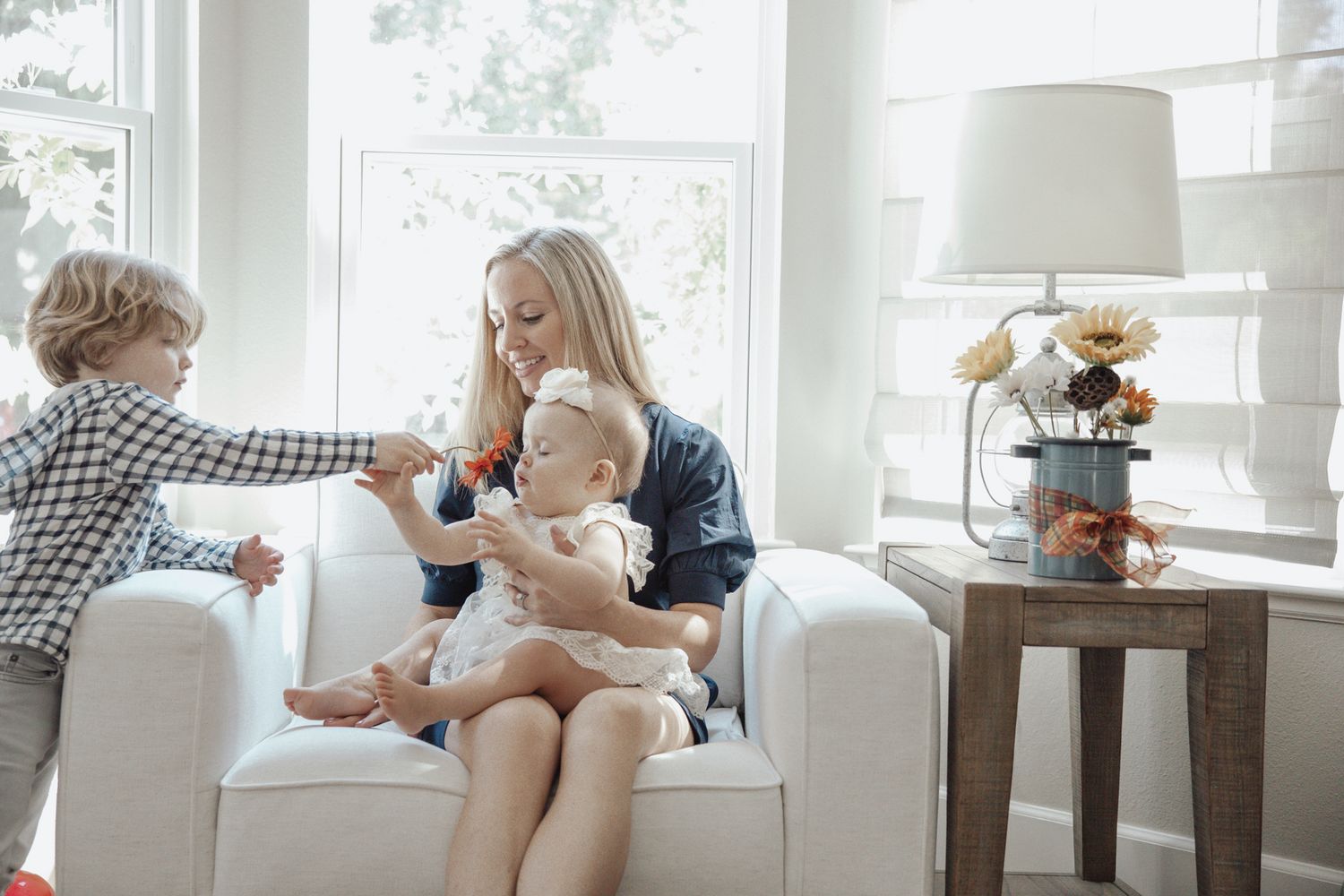 Family relaxing together on a white couch in a bright sunlit room.