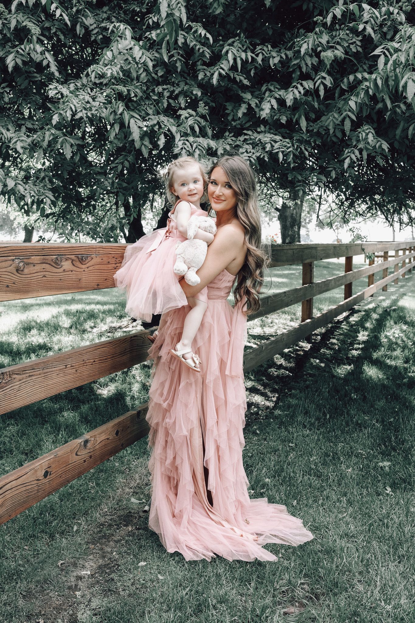 Candid moment of a mother and daughter embracing among roses at Jessie’s Grove Winery, highlighting the lush Oak Grove Flower Company garden