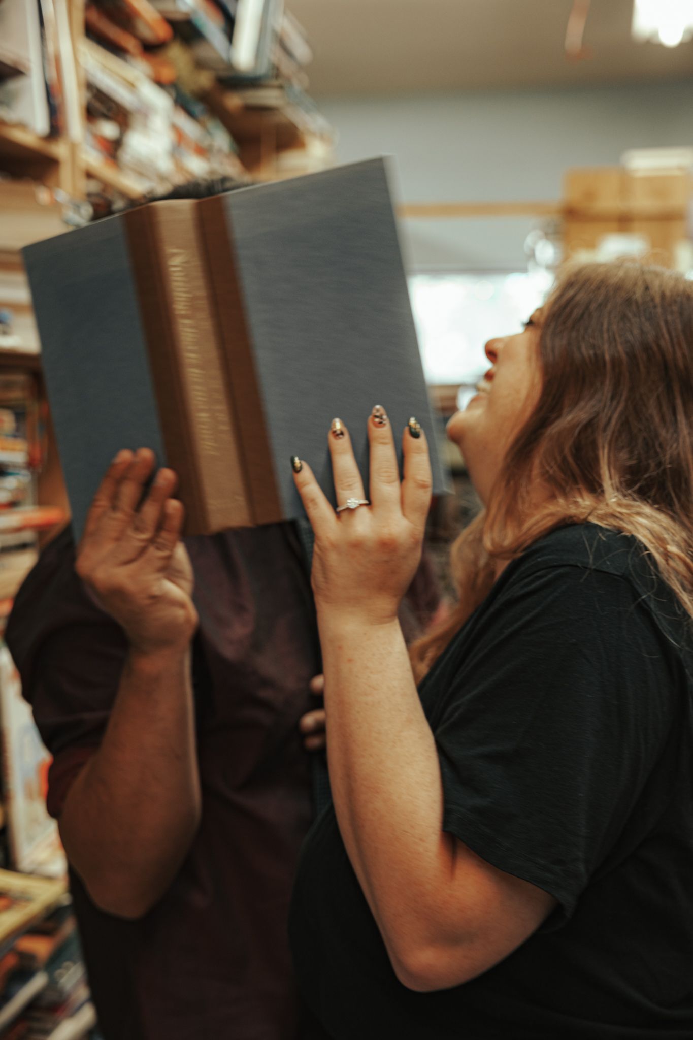 A sequence of images showing someone hiding their face behind a dark book in different angles.