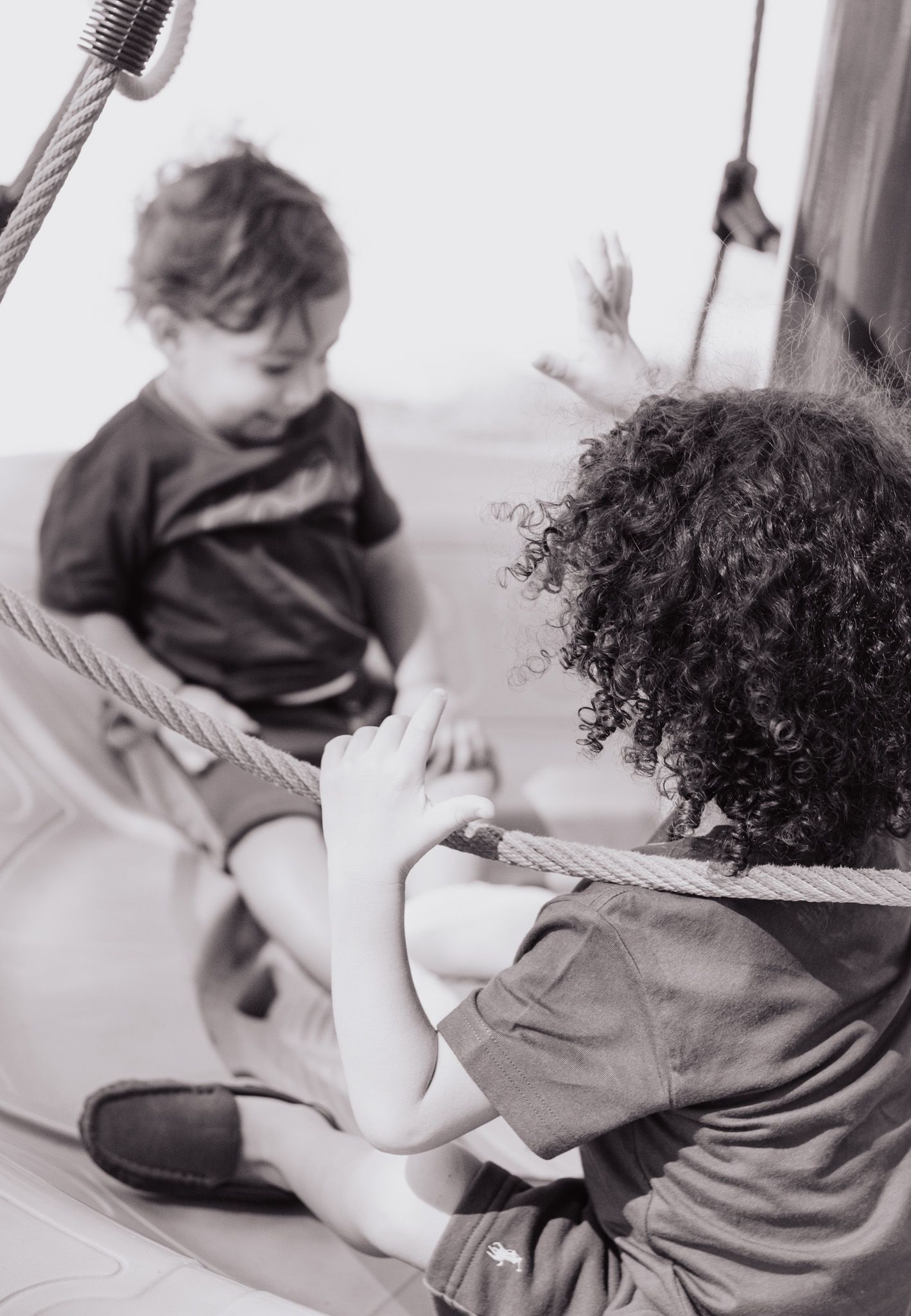 A sequence of black and white photos showing two children sitting together and interacting on a couch.