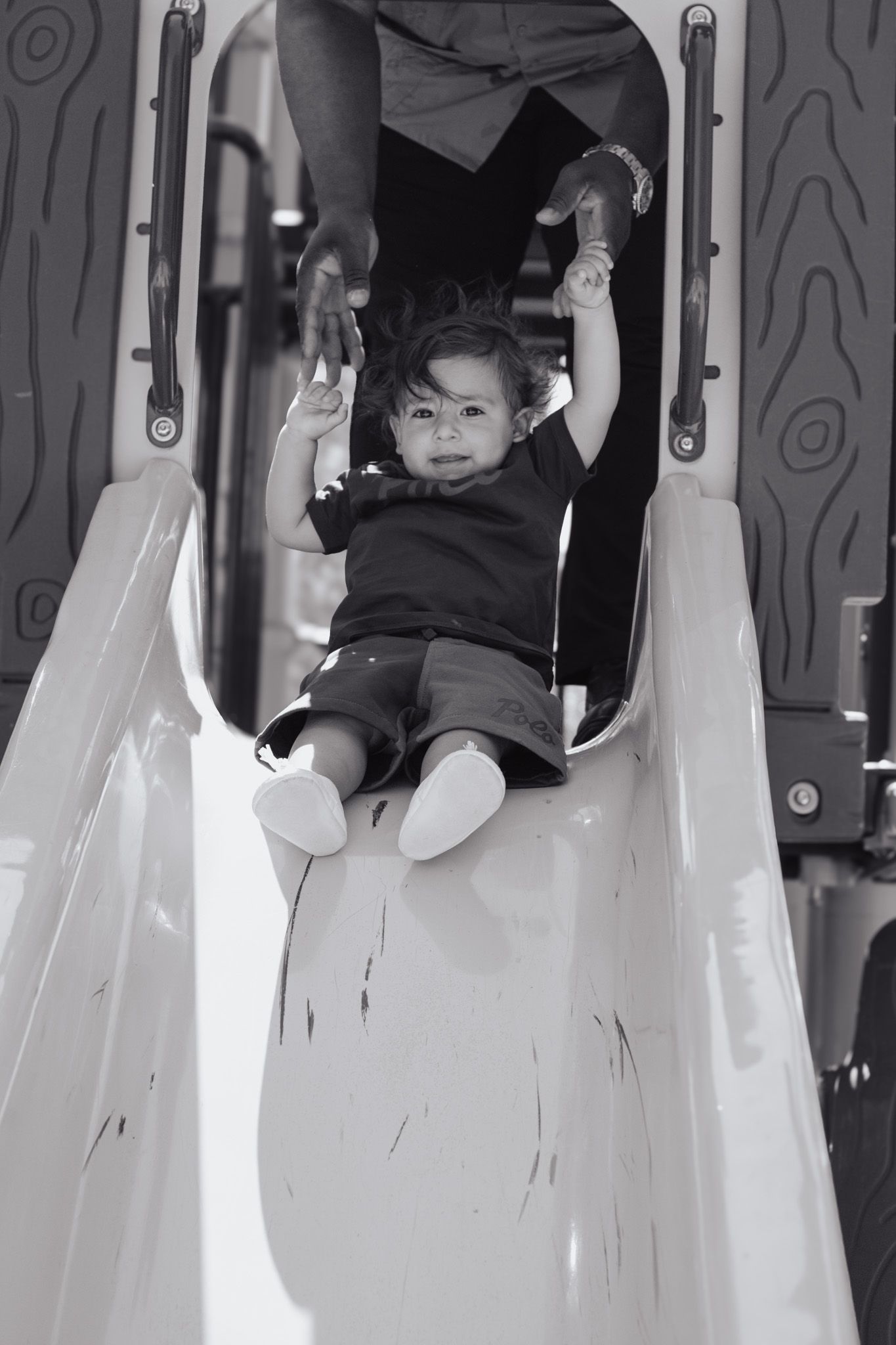 A young child in dark clothing plays inside a white art installation with curved walls and hanging elements.