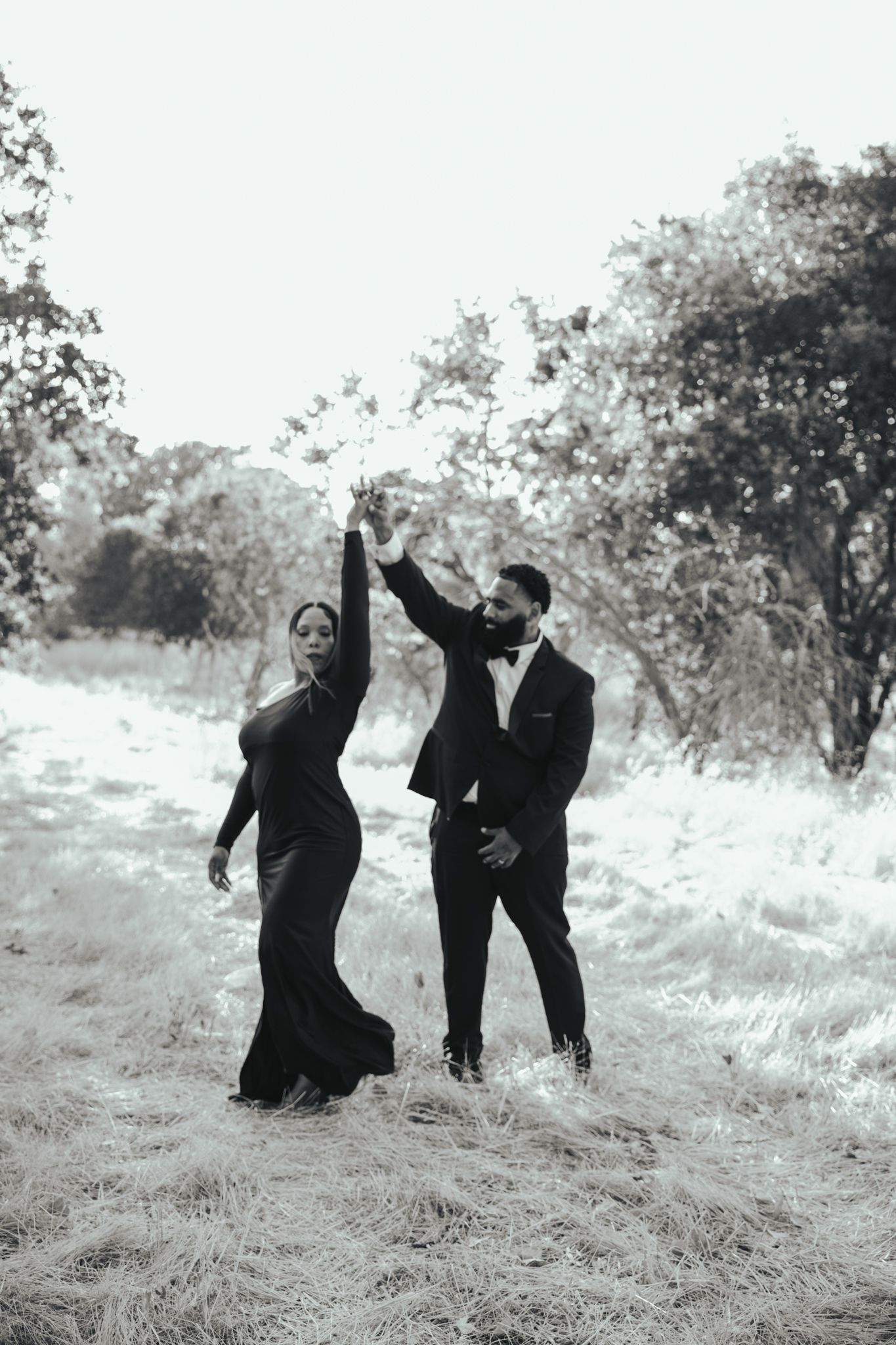 A series of black and white photos showing people playfully interacting on a grassy hillside in formal attire.