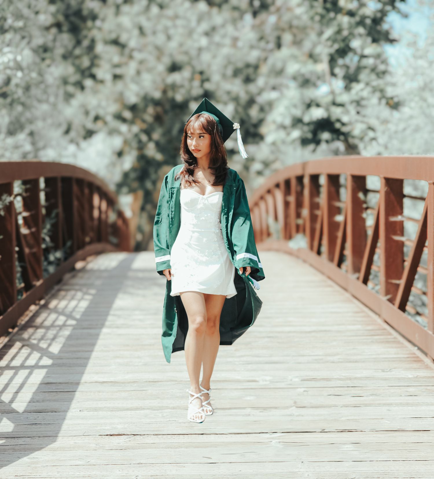 A set of photos showing a person in a teal jacket walking and posing on a wooden bridge in a hazy natural setting.