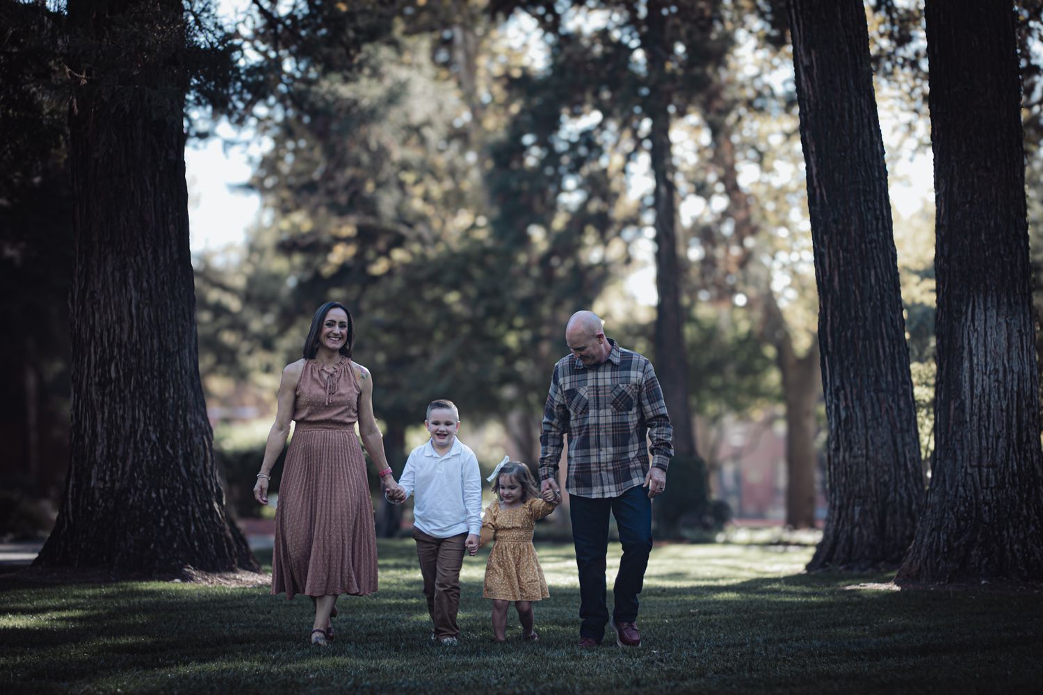 Family walking together at UOP in Stockton during fall minis, candid connection in golden morning light on October 17th.