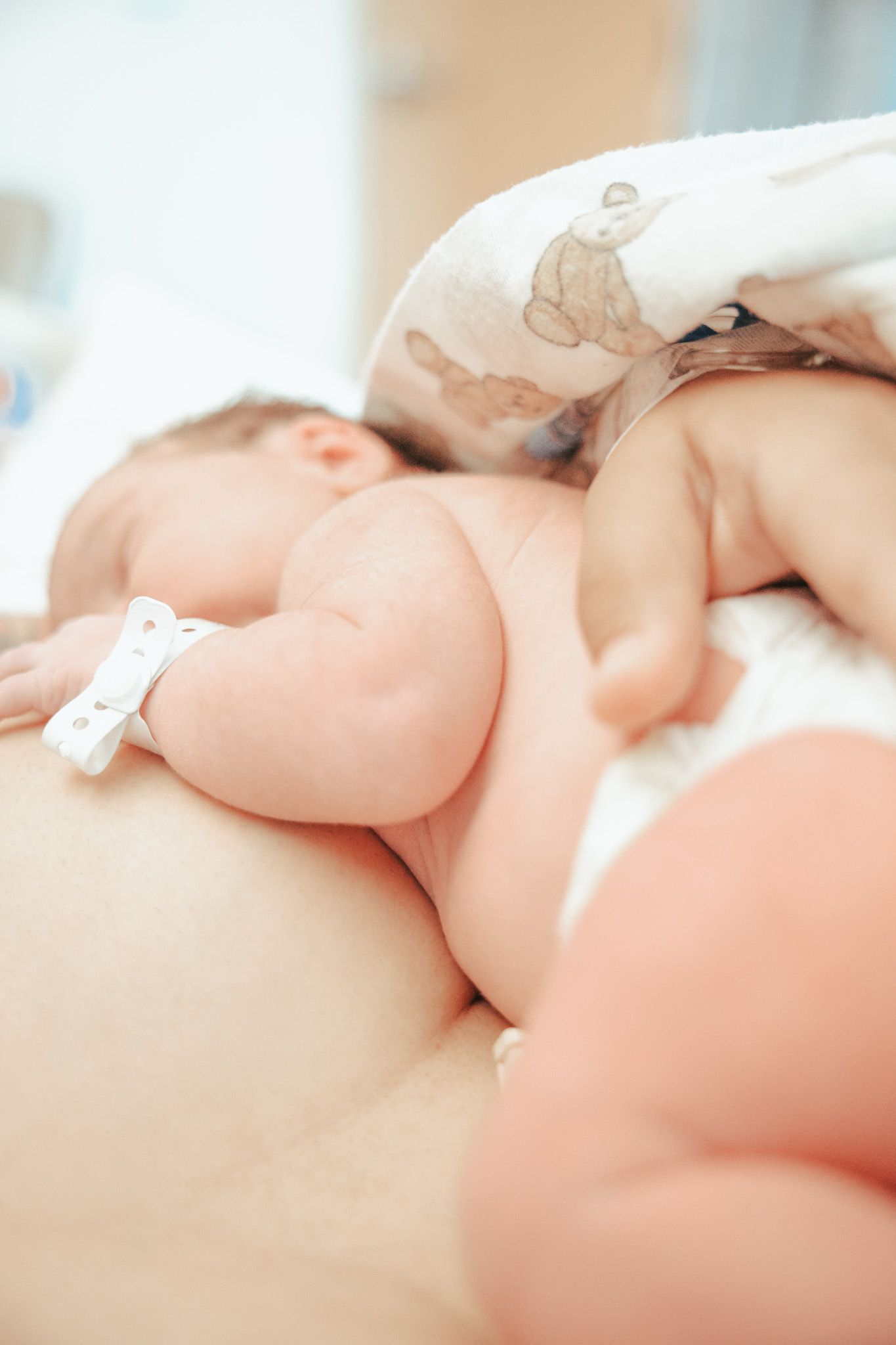 A newborn baby sleeping peacefully on white bedding while receiving a gentle massage.