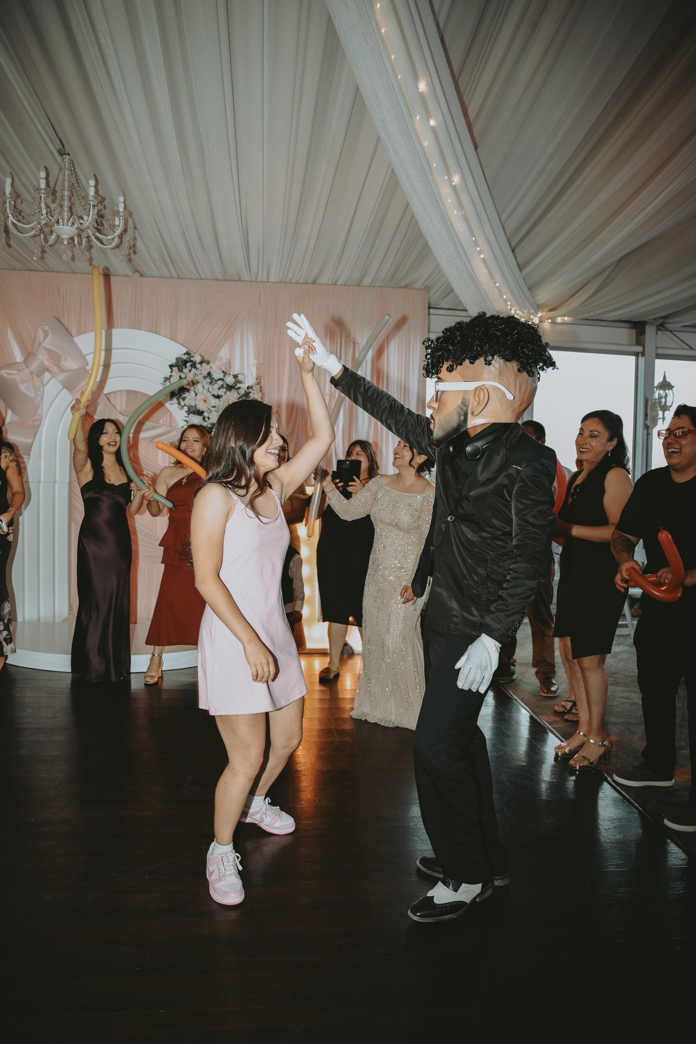 Candid quinceañera photo of the birthday girl dancing with the DJ entertainment team, vibrant lighting, upbeat music, and a lively celebrati
