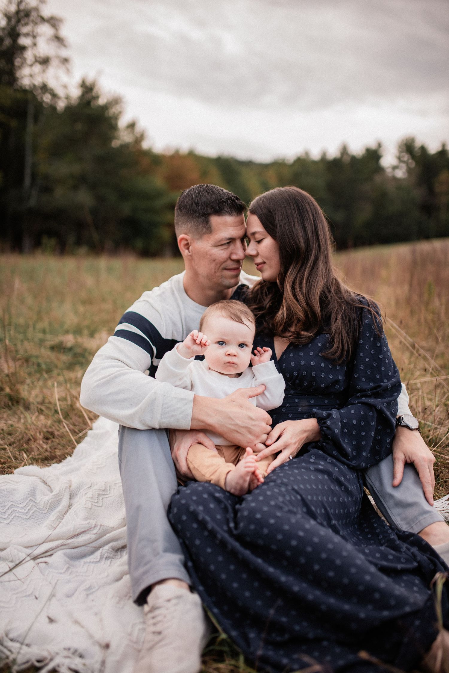 Family sitting in a grassy field with their baby during a lifestyle outdoor session by Schuylkill County photographer R&J Photography