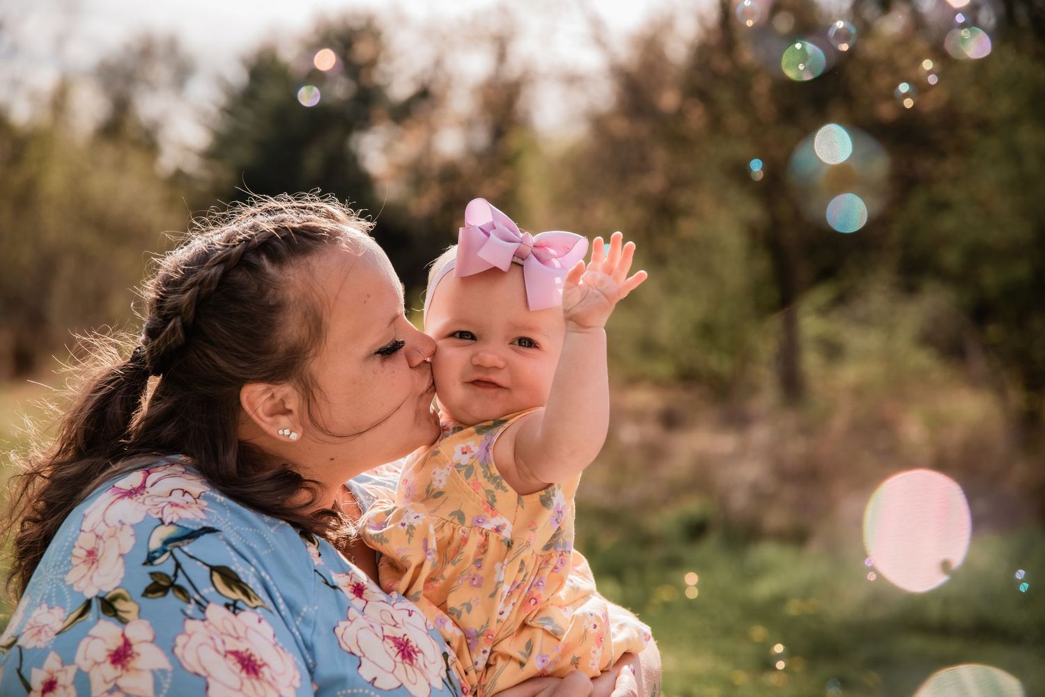 Mother and daughter hug and play with bubbles in summer sunlight in field in Schuylkill County Pennsylvania