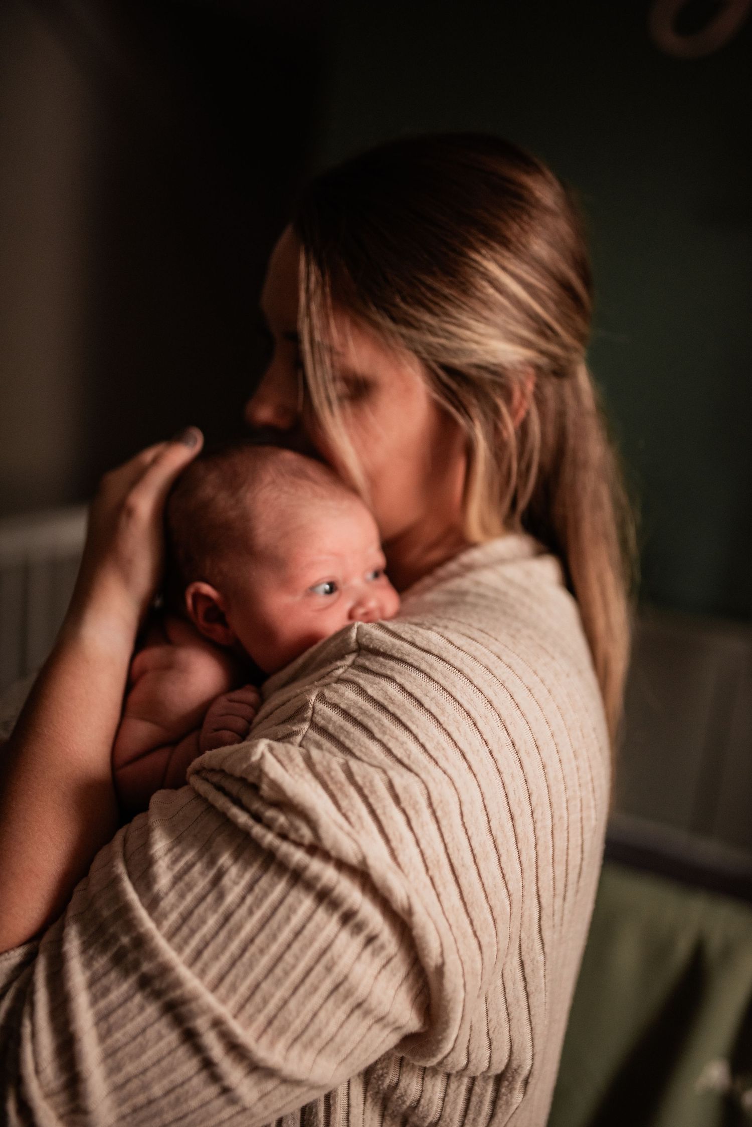 Young mother snuggles newborn babe softly by warm window light in in home newborn photo session in Delano Pennsylvania with R&J Photography