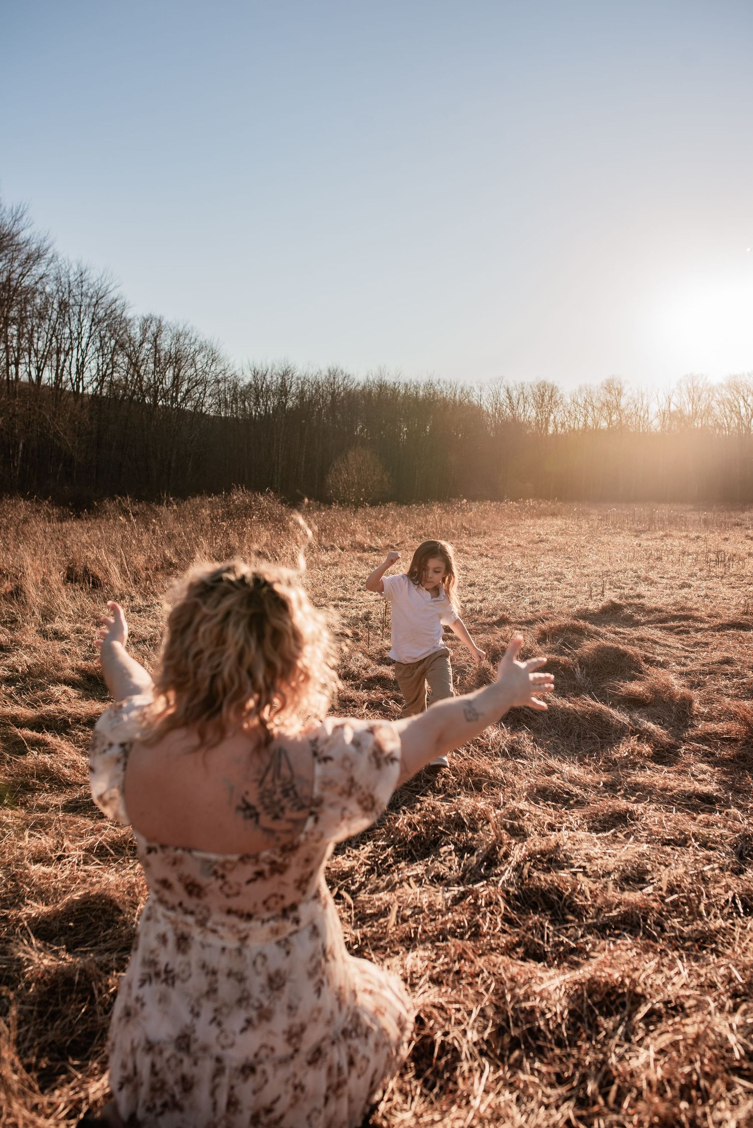 mother and son play and run to each other in field during golden hour family photo session in Schuylkill county with R&J Photogrpahy