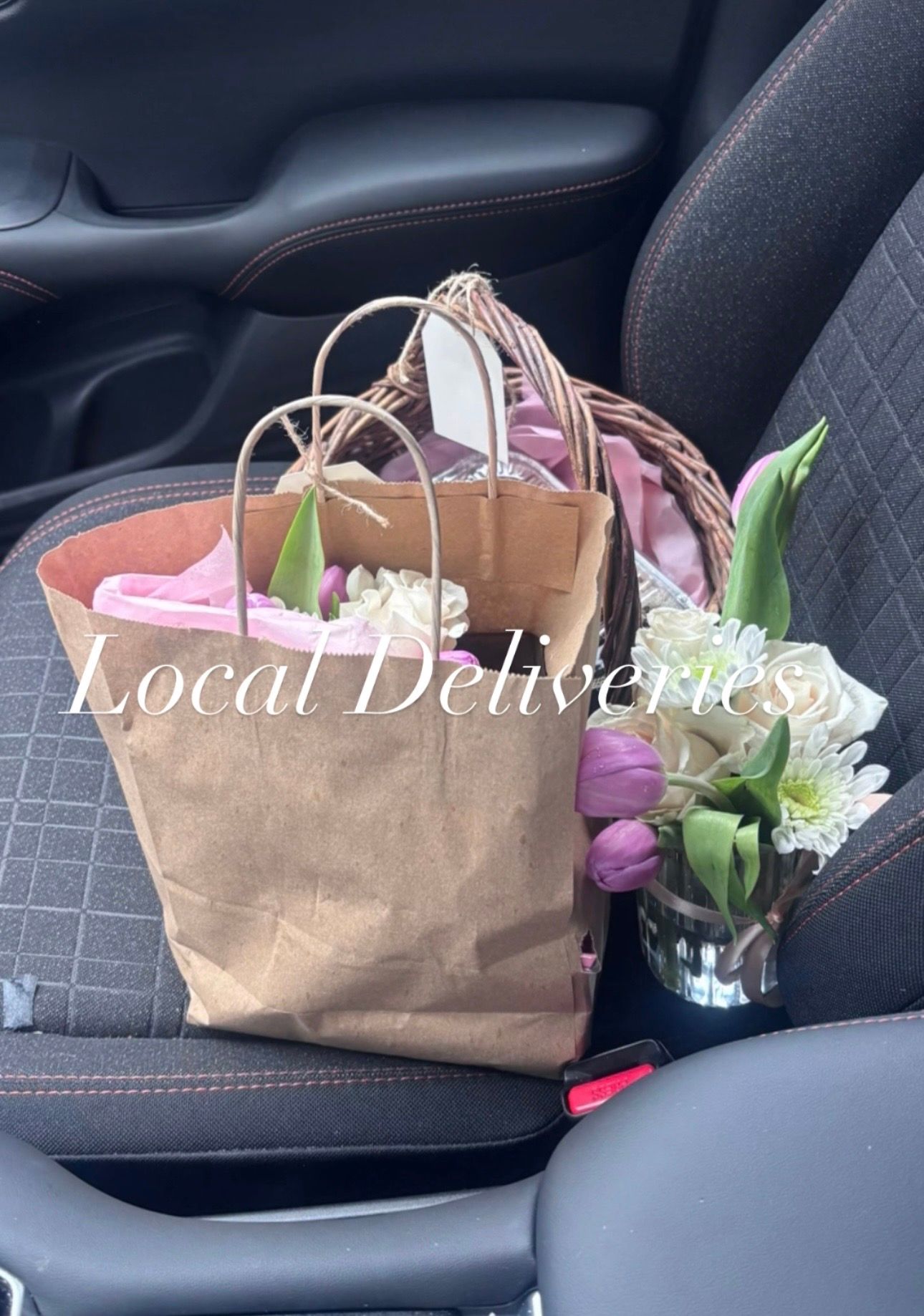 A brown paper bag and vase of purple tulips on a car seat with text reading Local Deliveries.