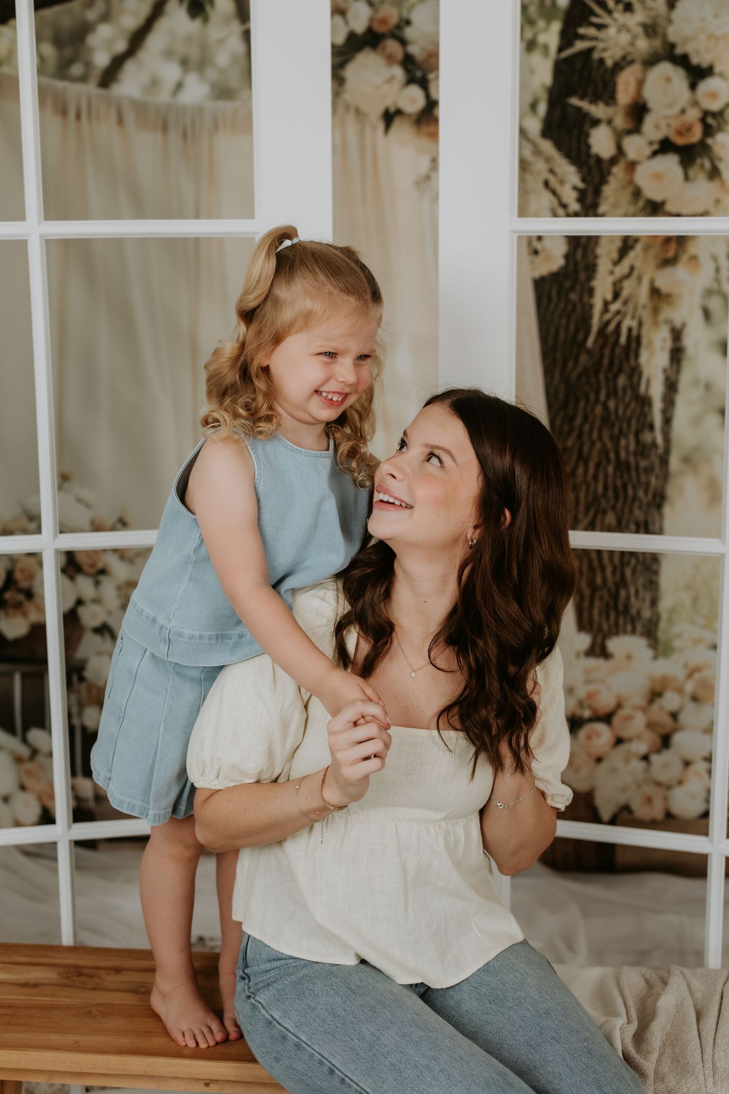 A tender moment captured between parent and child in a light-filled room with floral decor.
