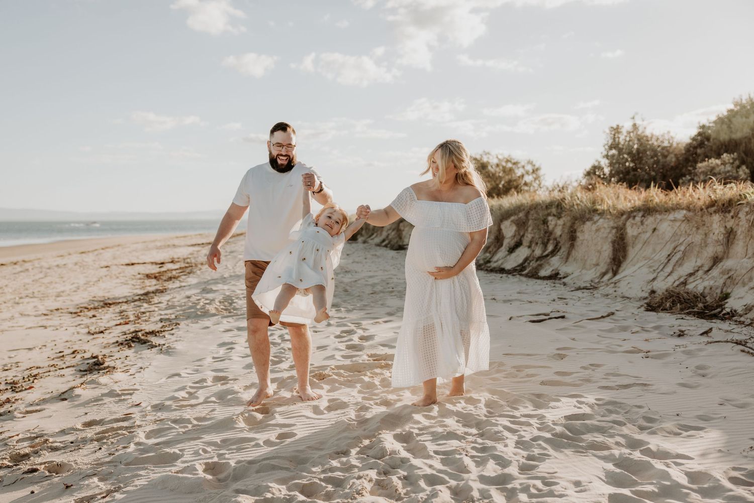 Family walking along scenic beach with cliffs during sunset photo session.