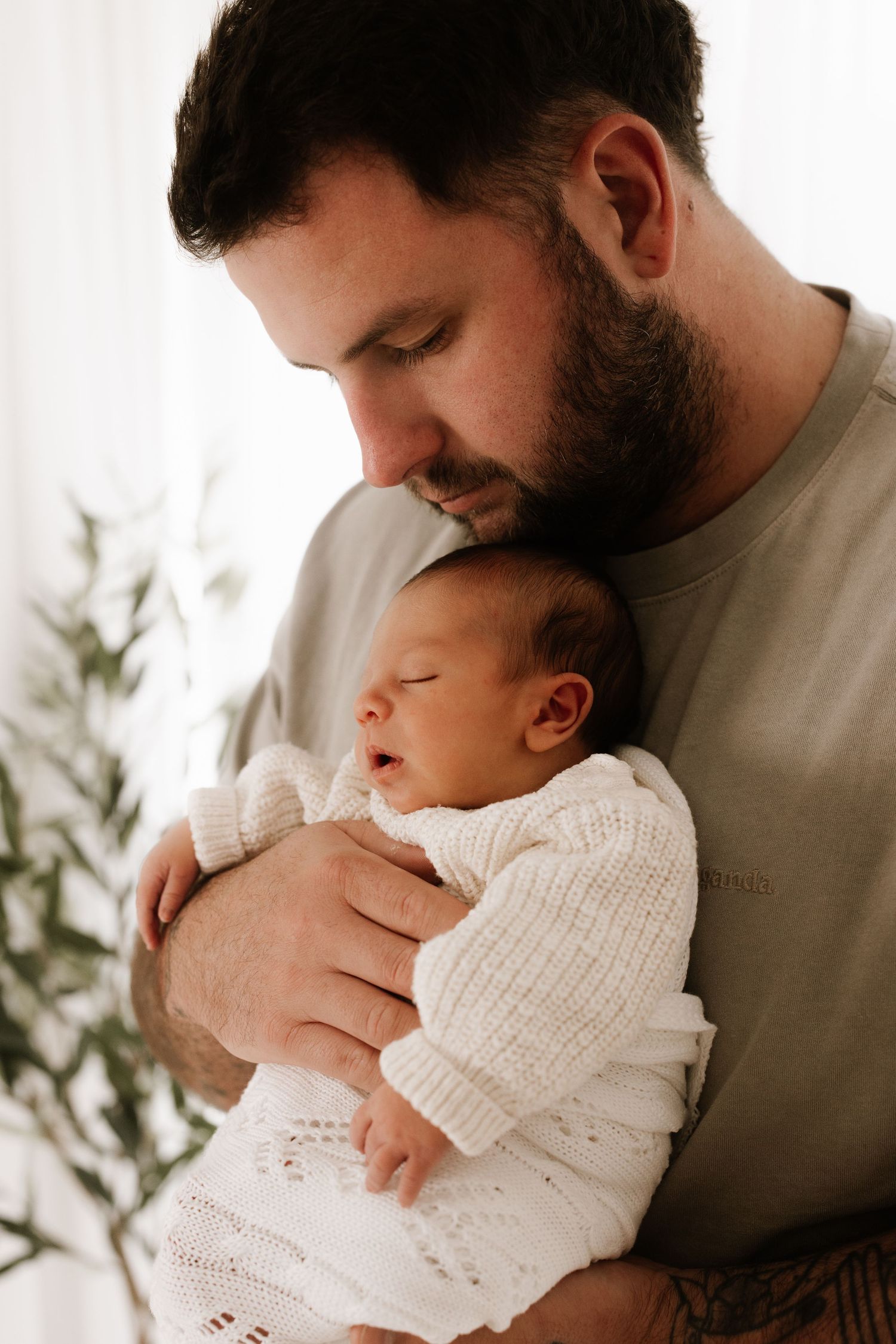 Tender moment between parent and baby in white knit sweater.