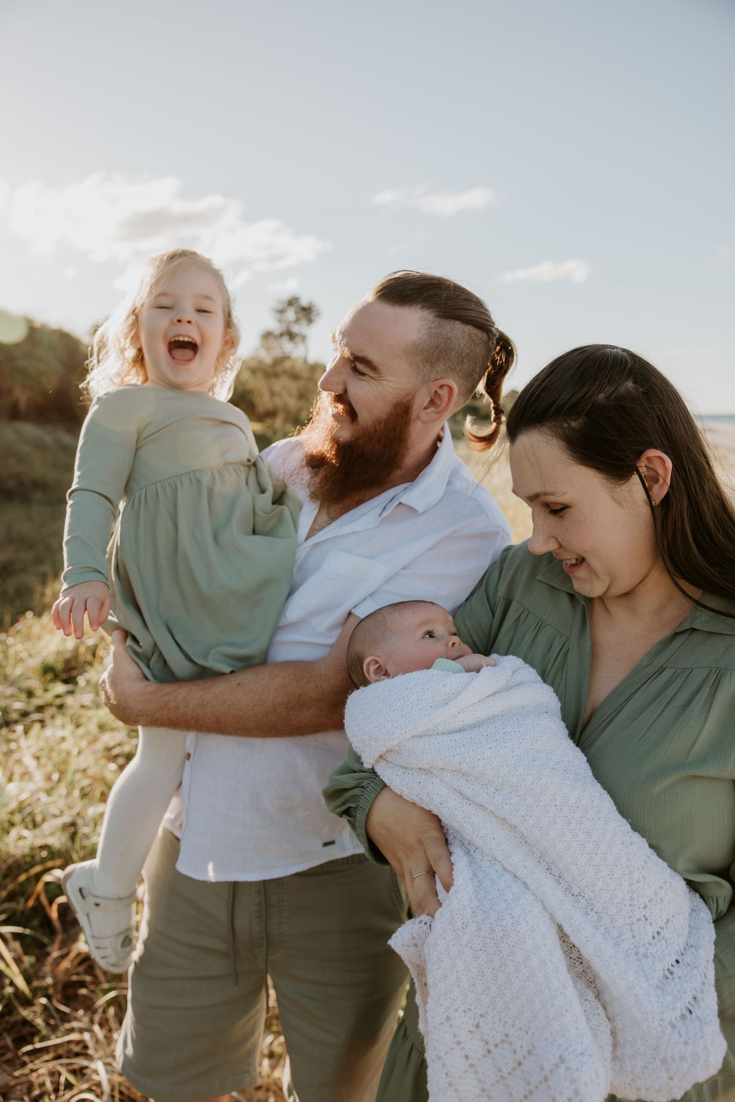 Family portrait session featuring joyful interactions and laughter in golden sunlight.
