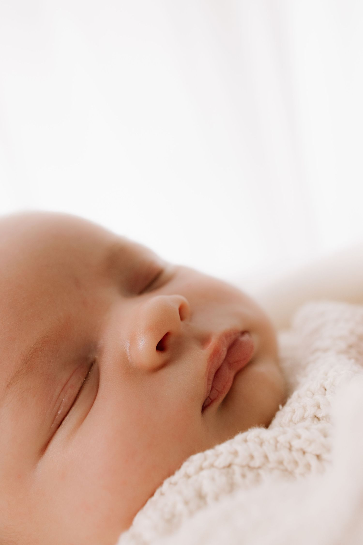 Peaceful sleeping infant wrapped in soft white blanket.