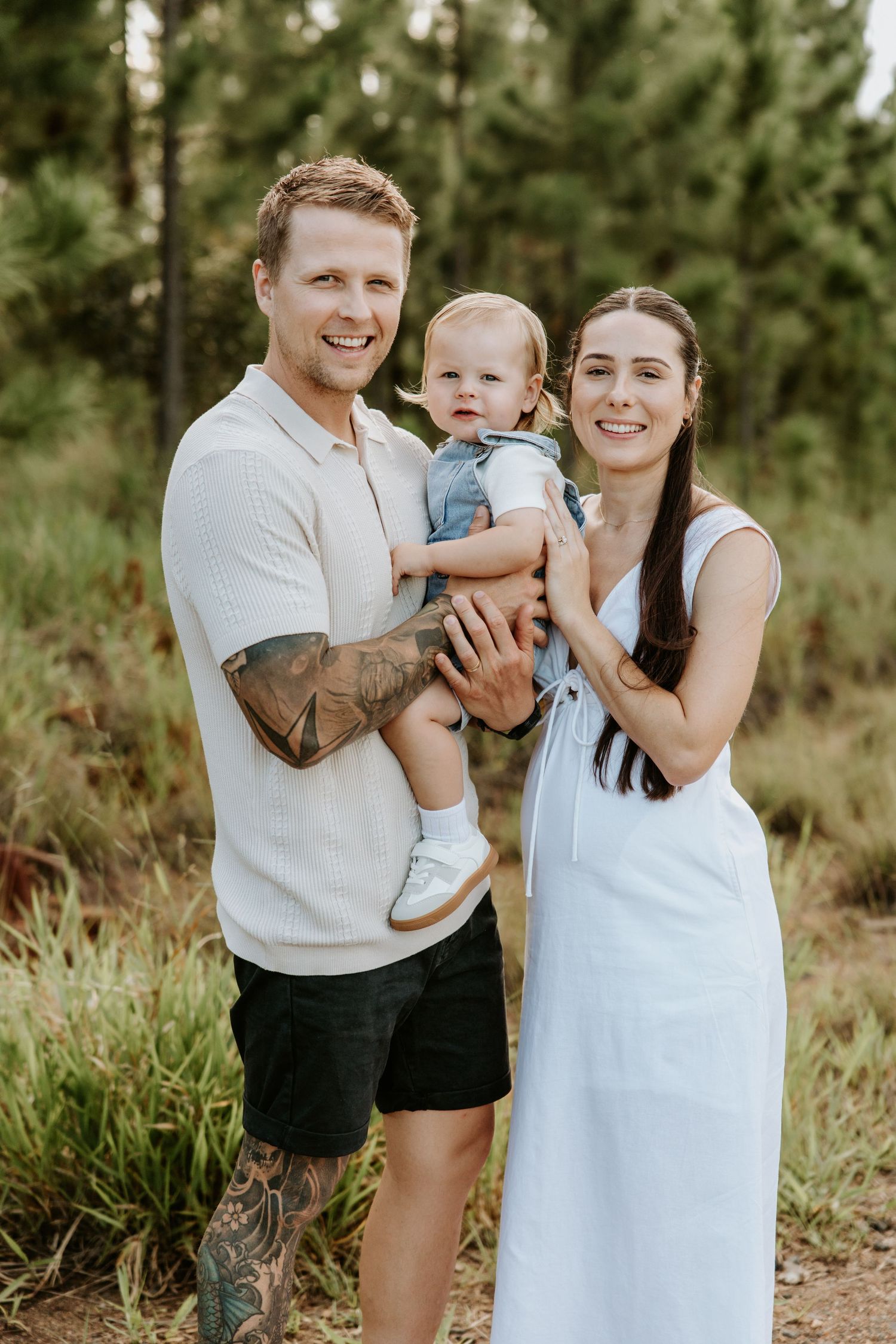 Family enjoying a playful outdoor photoshoot in a natural setting with pine trees in the background.