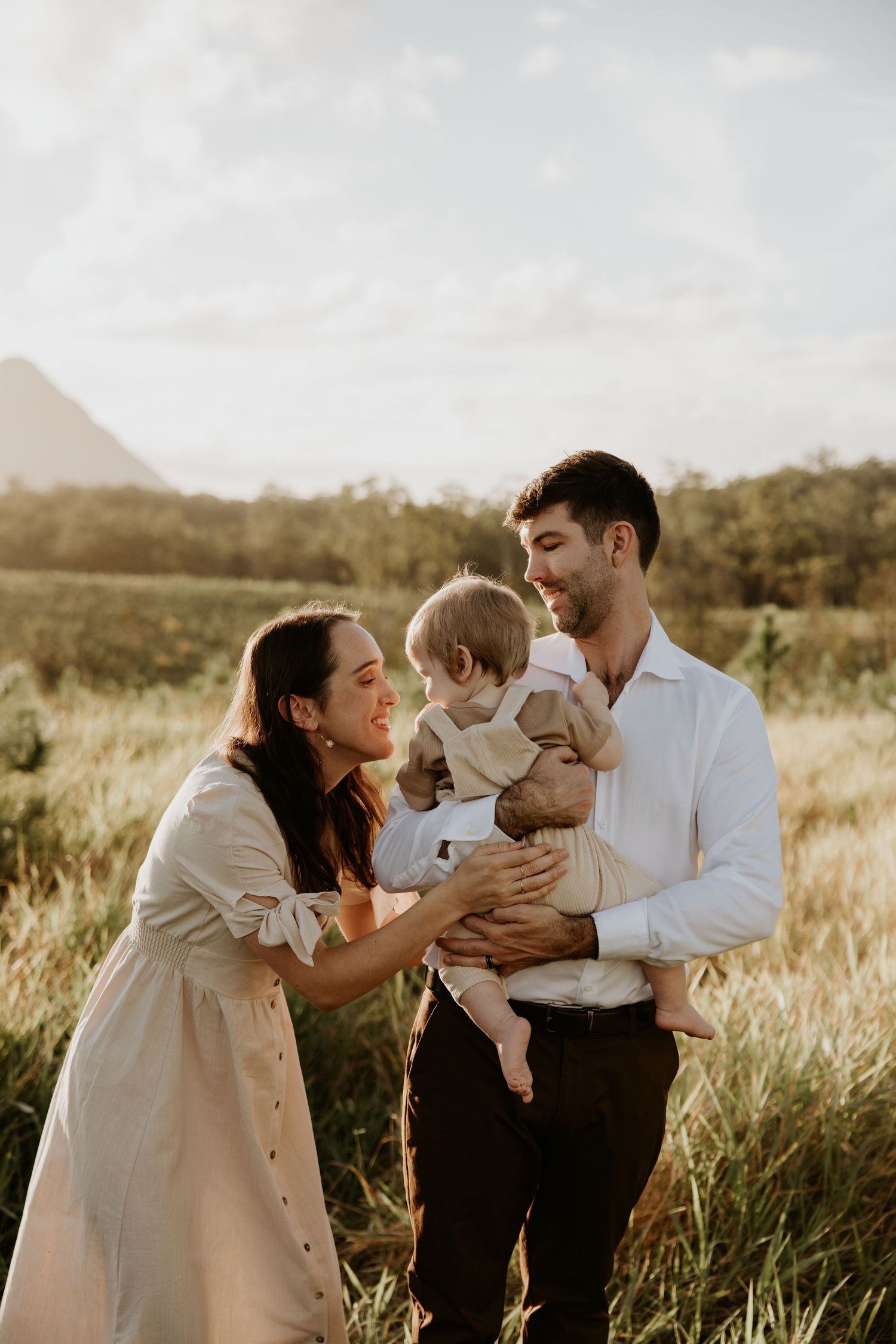 Family sharing intimate moments together in a sunlit field during sunset.