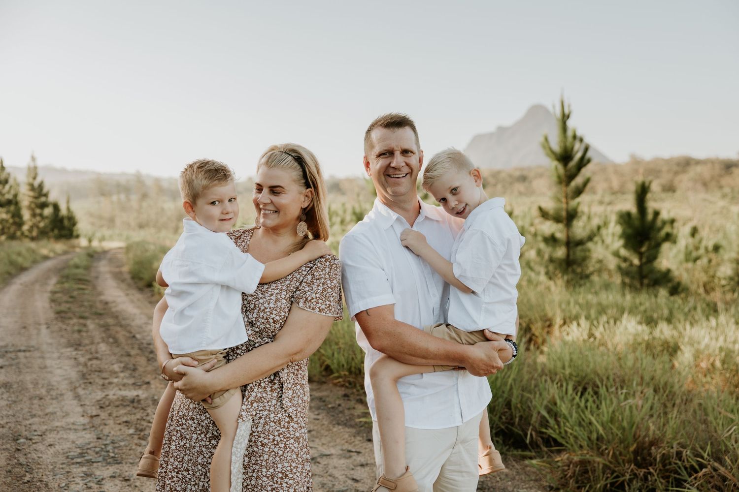 Family group portrait in casual attire against natural outdoor setting.
