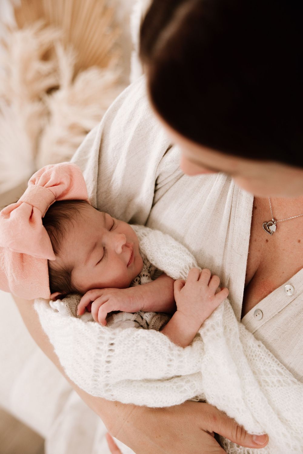Newborn baby sleeping peacefully on soft white textured blanket.