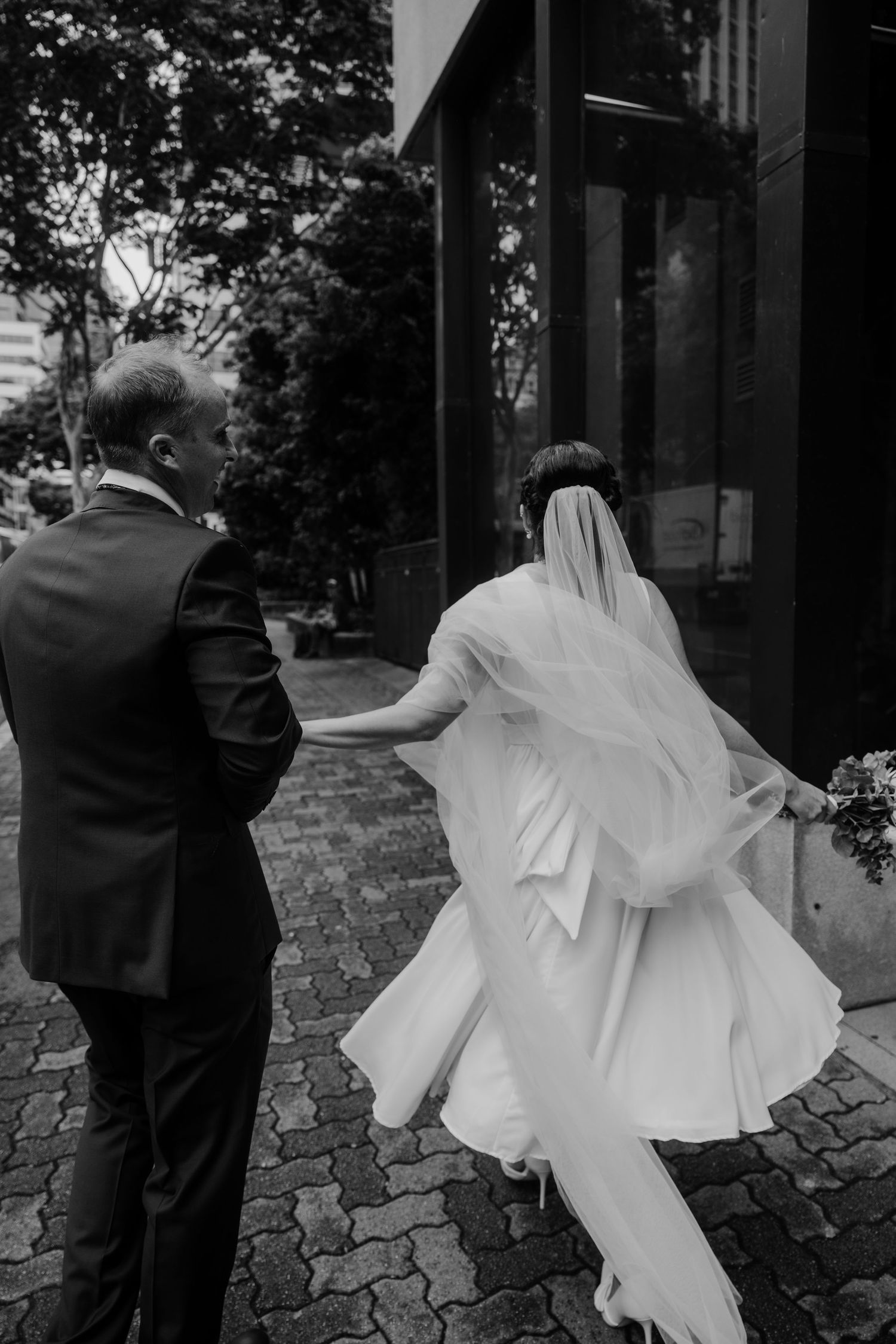 Wedding couple dances and twirls on cobblestone path in dramatic black and white photography.