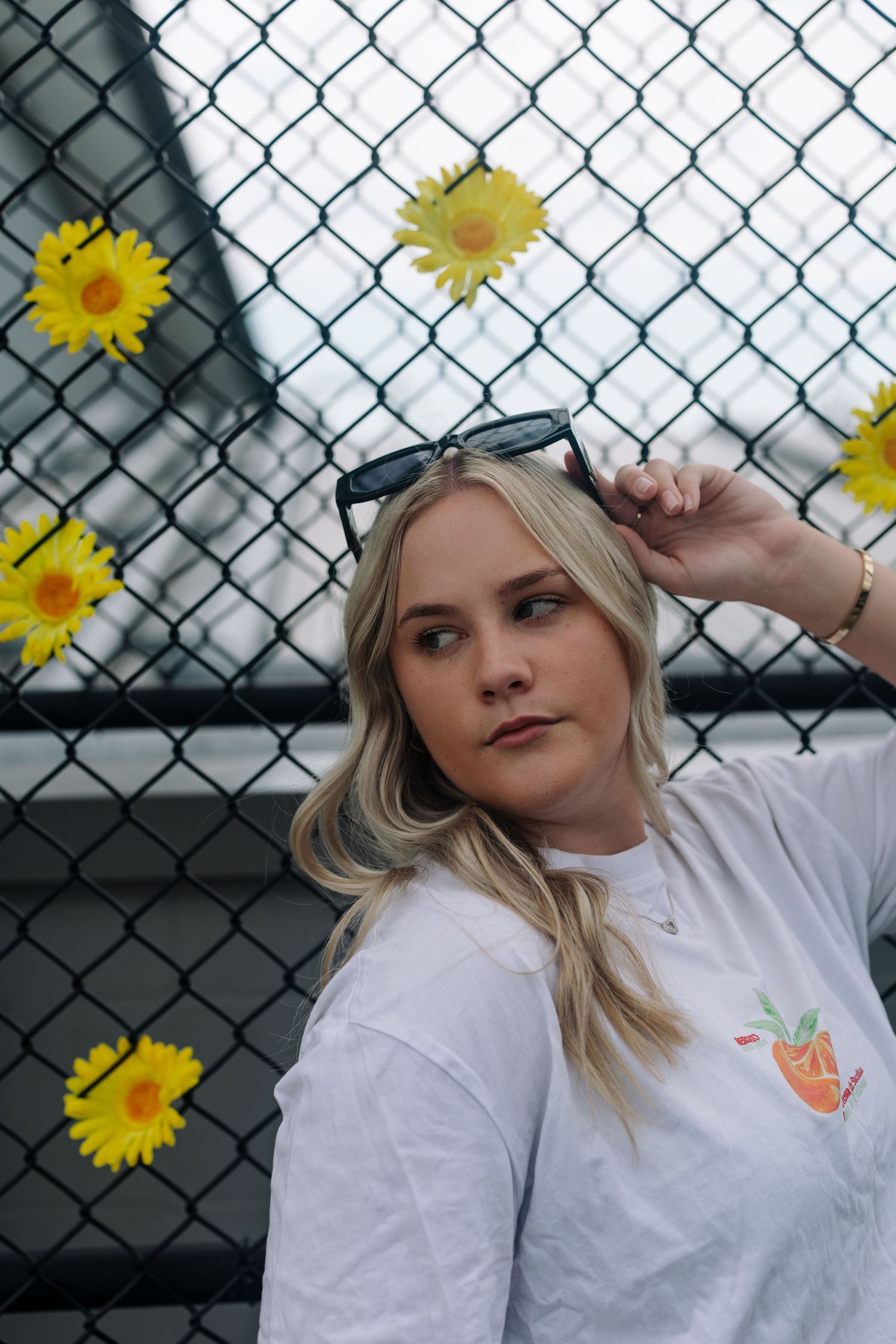 Portrait against a chain link fence decorated with yellow sunflowers.