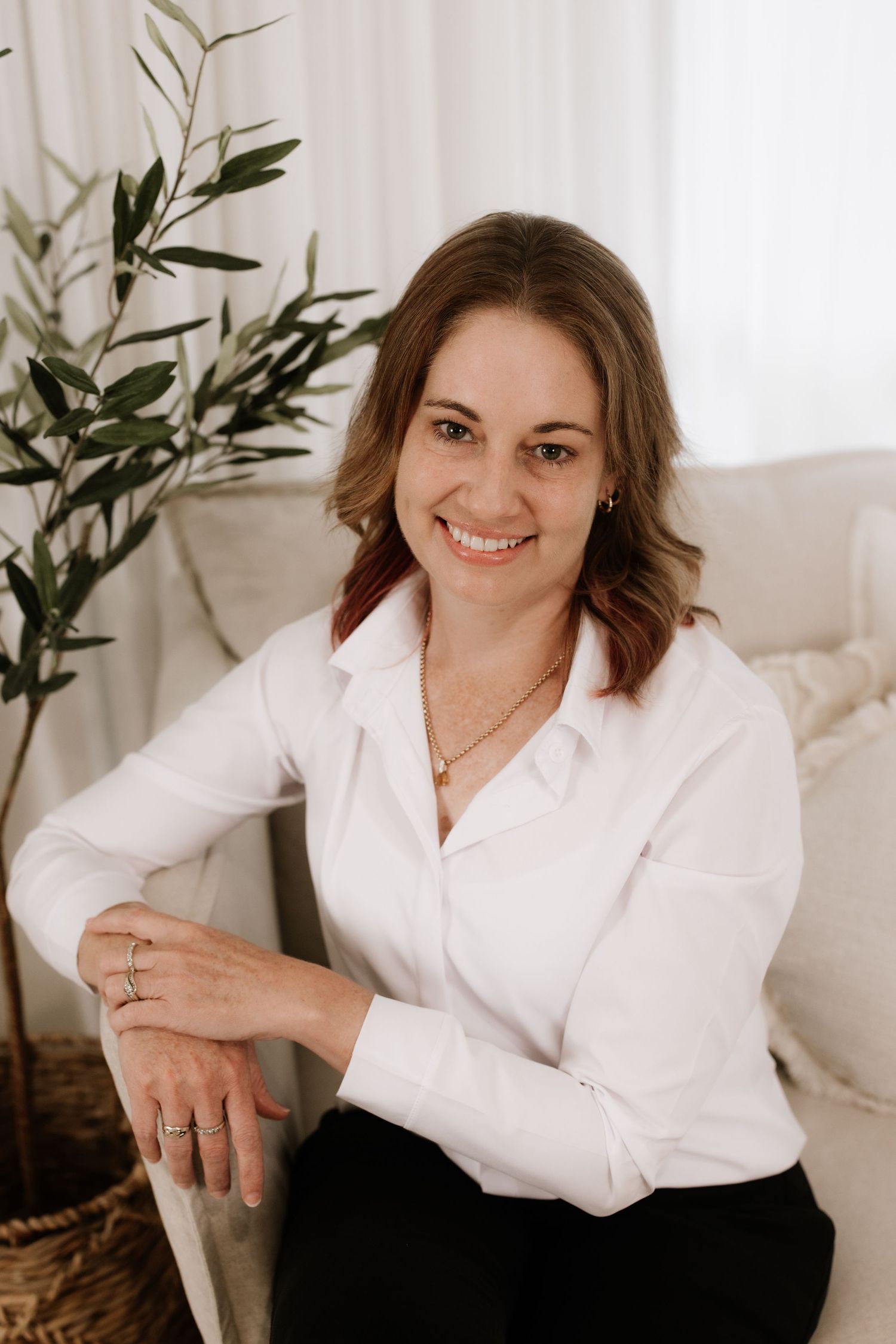Professional portrait series in white shirt against neutral background with olive plant accents.
