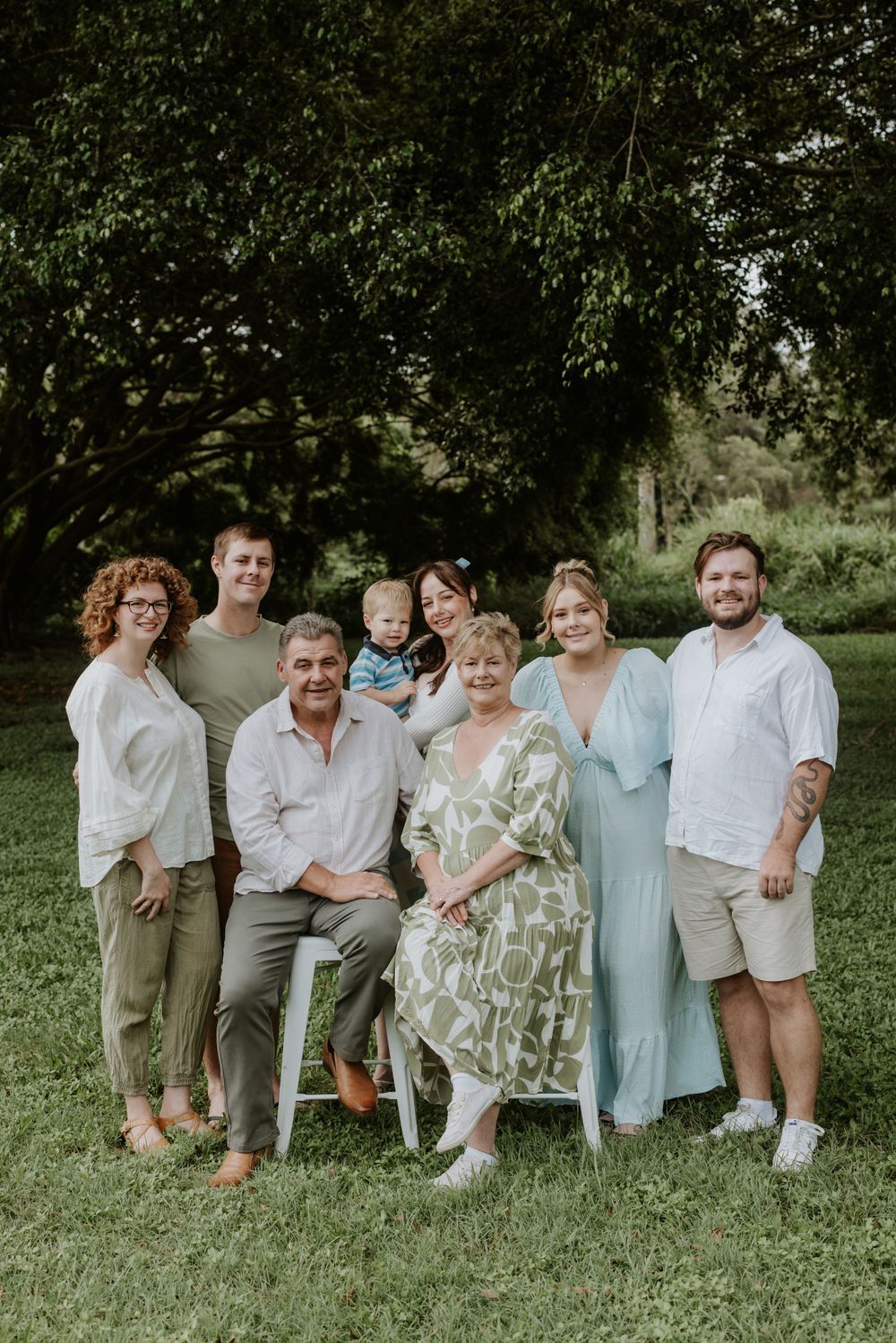 Casual outdoor family gathering with everyone seated on chairs in a lush green garden setting.