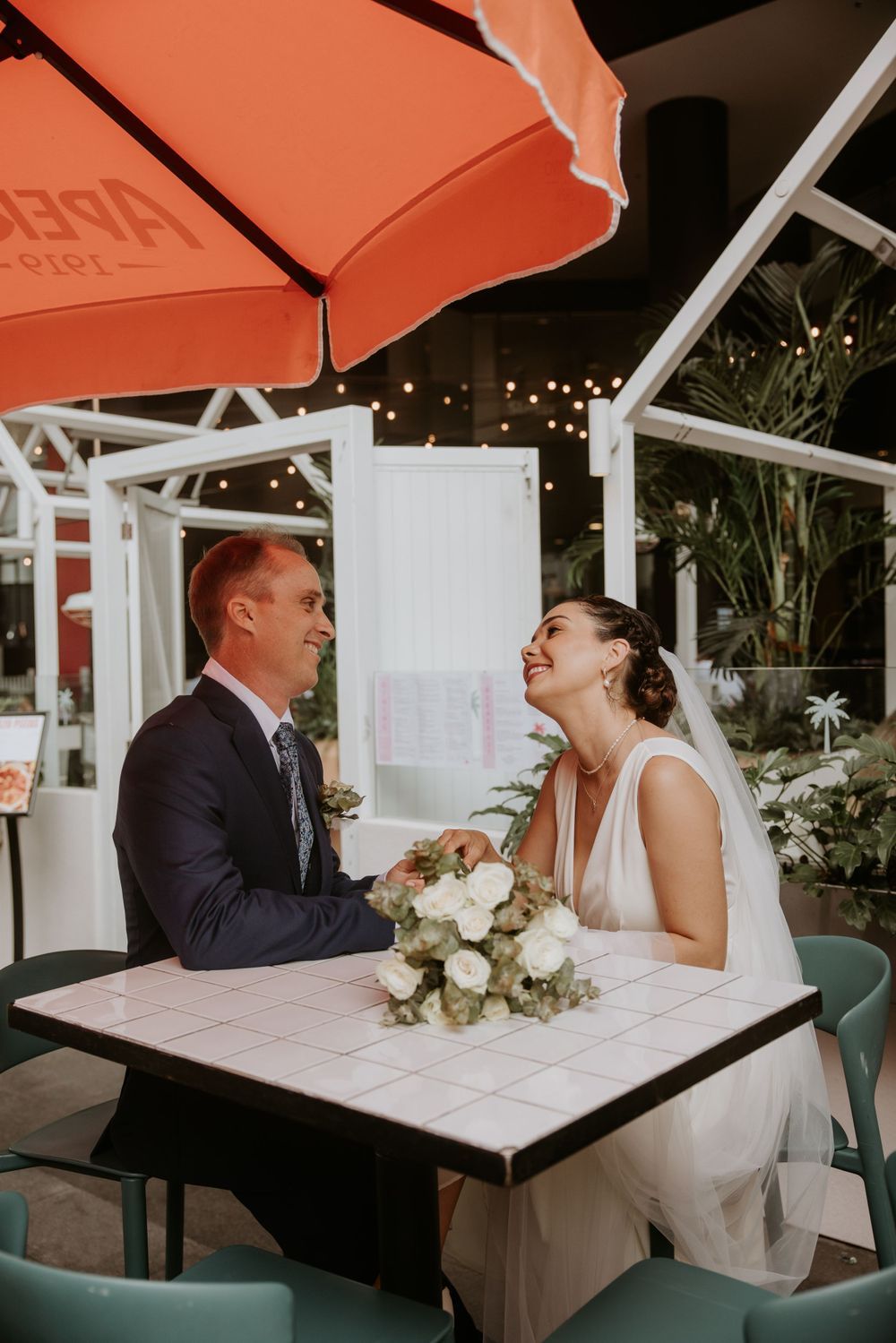 Couple sharing a moment at a cafe table under orange umbrellas.