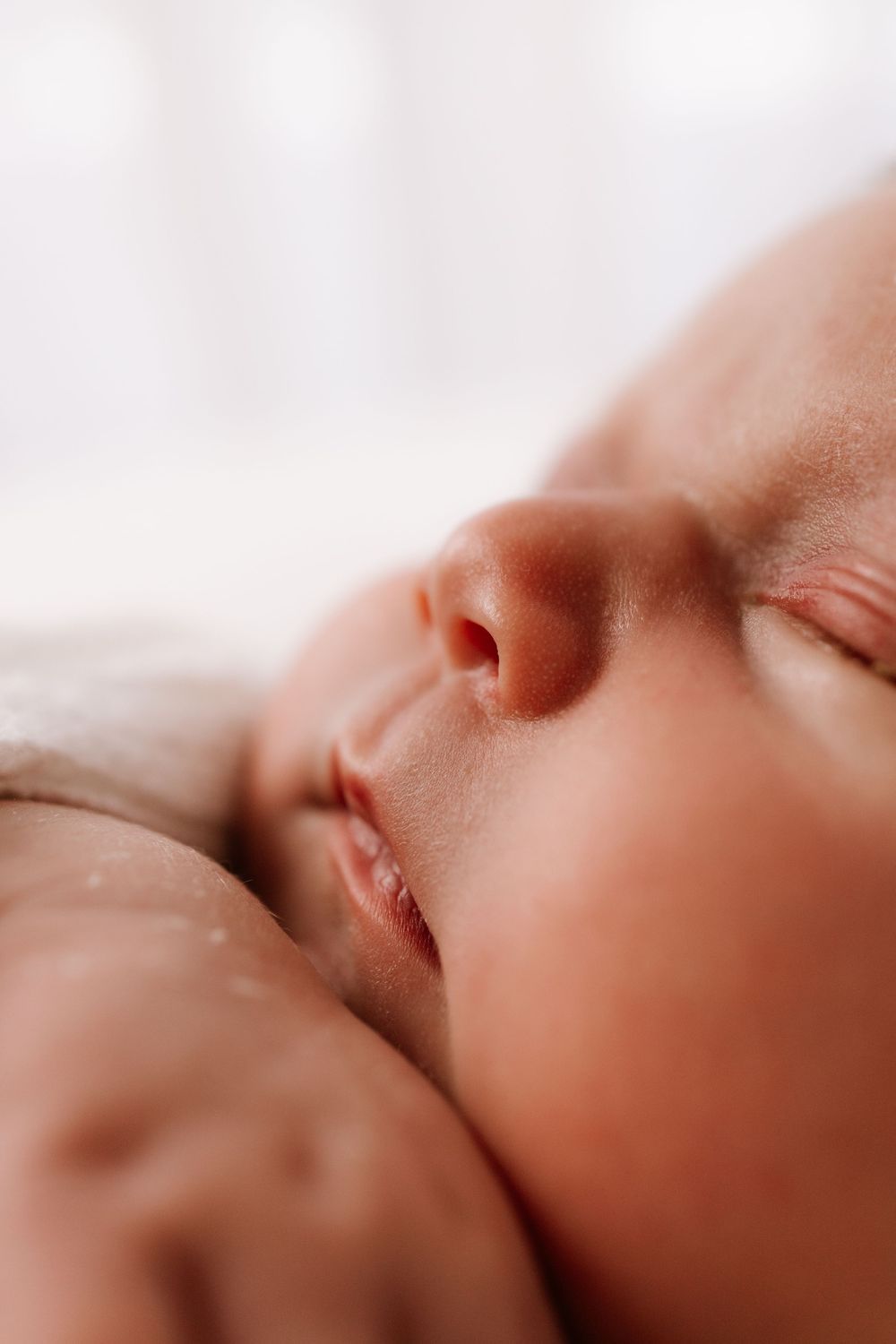 Extreme close-up macro photography of newborn baby features in soft lighting.