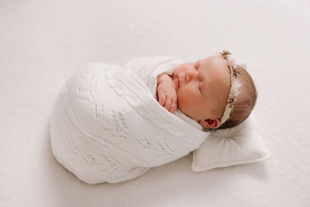 A series of intimate newborn portraits in soft white tones showing tender moments.