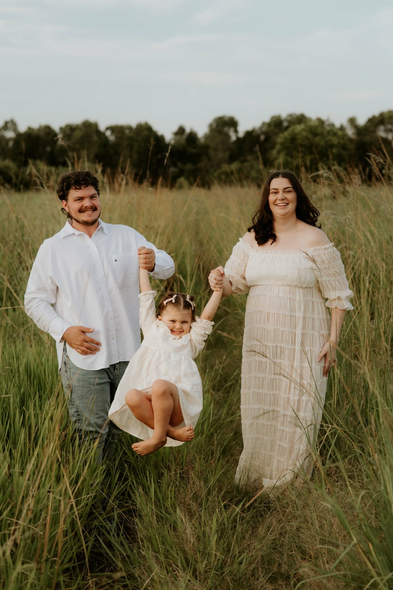 A family photoshoot in a tall grass field showing playful moments and laughter.