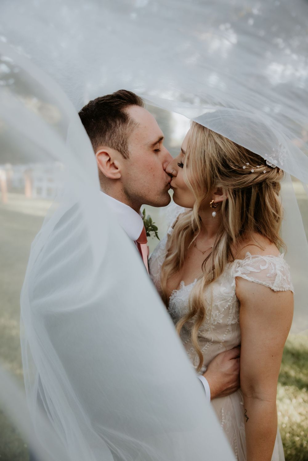 Romantic wedding couple sharing intimate kisses in dreamy outdoor setting.