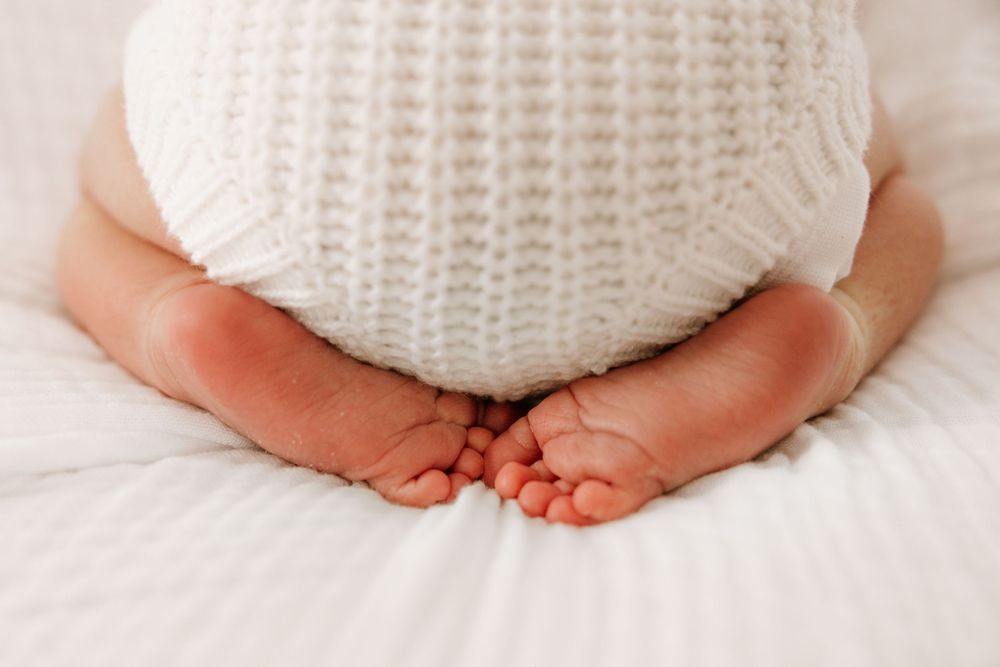 Close up of tiny baby feet against white knitted texture.
