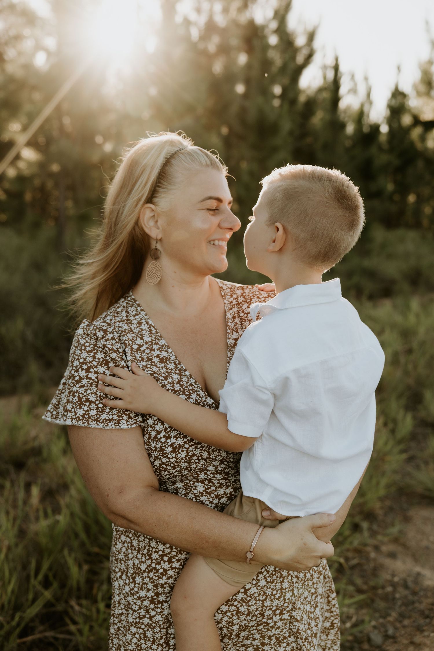 Mother and child share tender moments during sunset photoshoot in natural outdoor setting.
