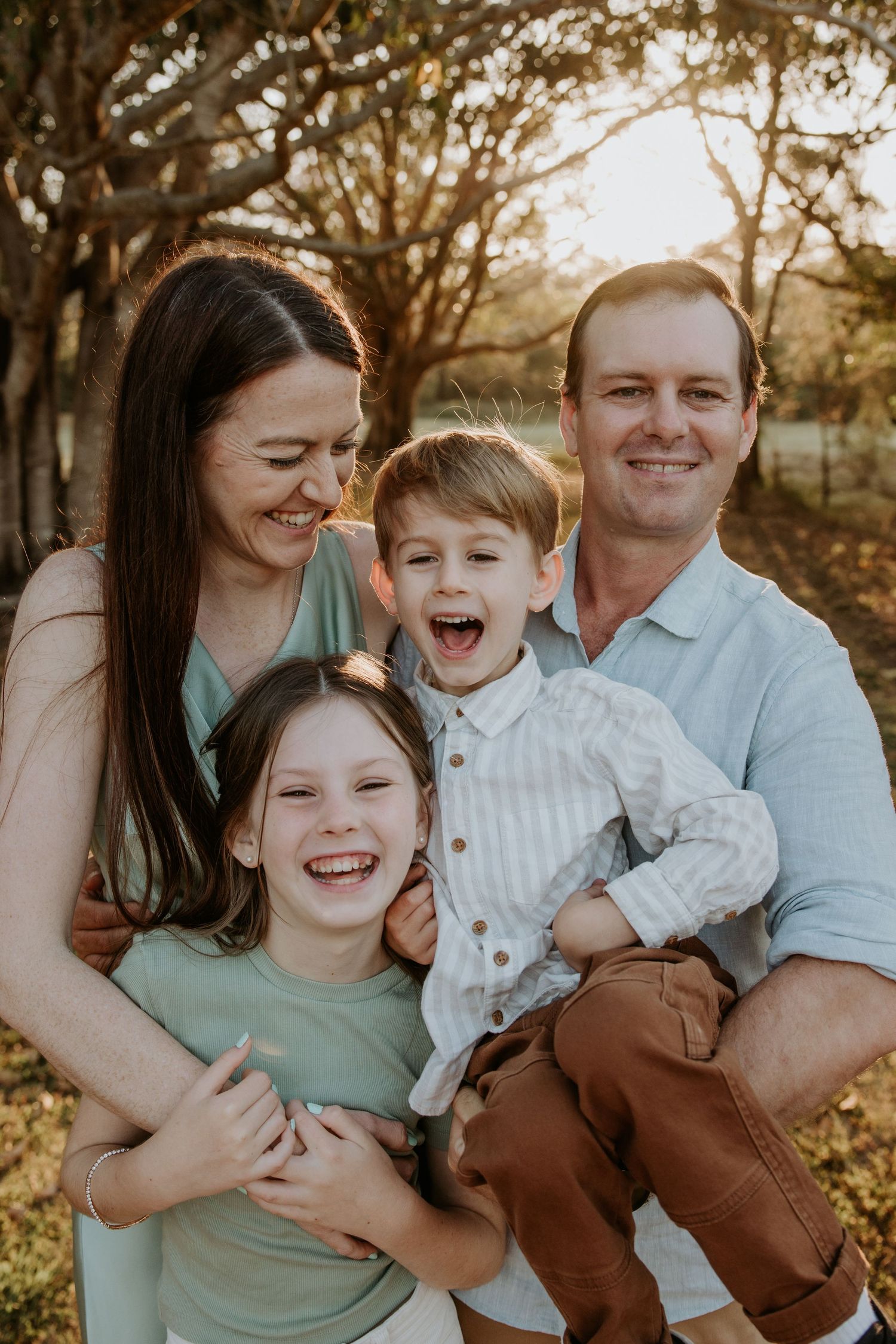 Family sharing laughs and embraces during outdoor photo session.