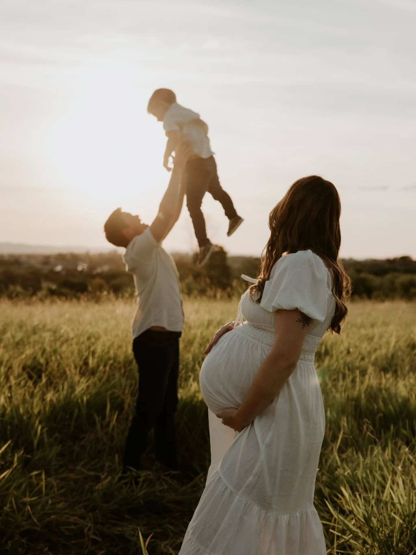 Silhouettes of people dancing and playing in a grassy field at golden hour.