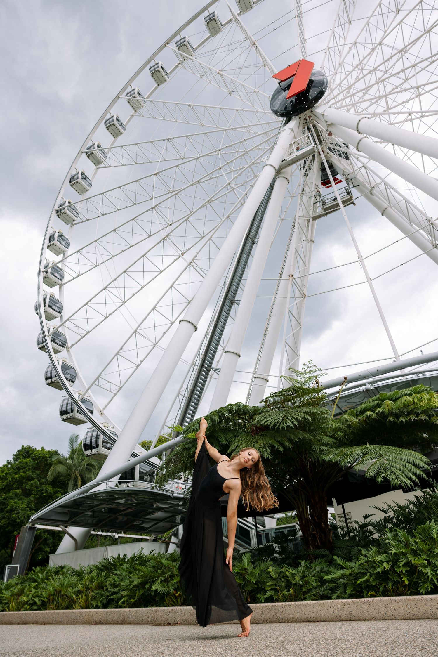 Artistic dance sequence in front of large Ferris wheel with dramatic movements.