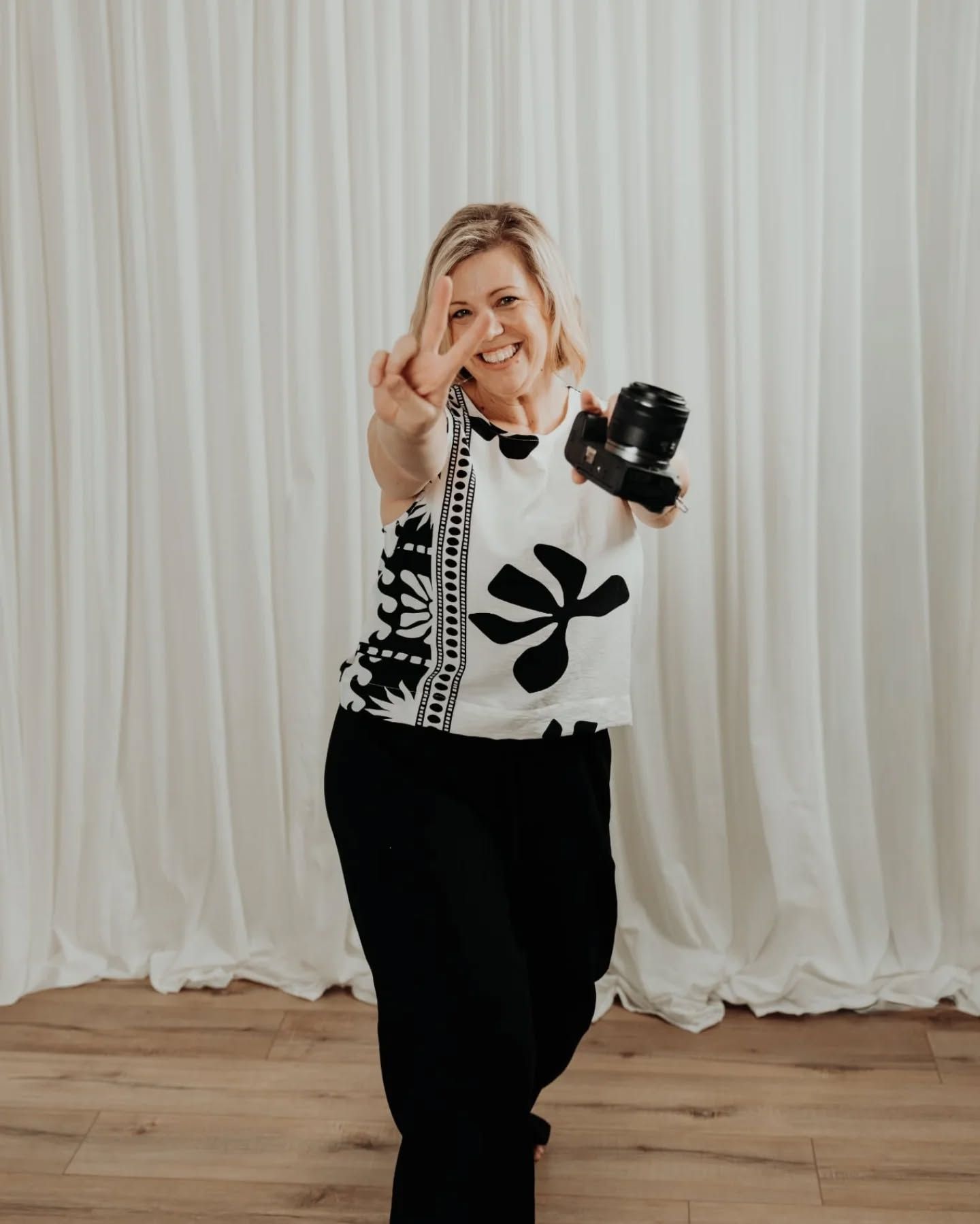 Stylish black and white outfit with floral pattern against white curtain backdrop.