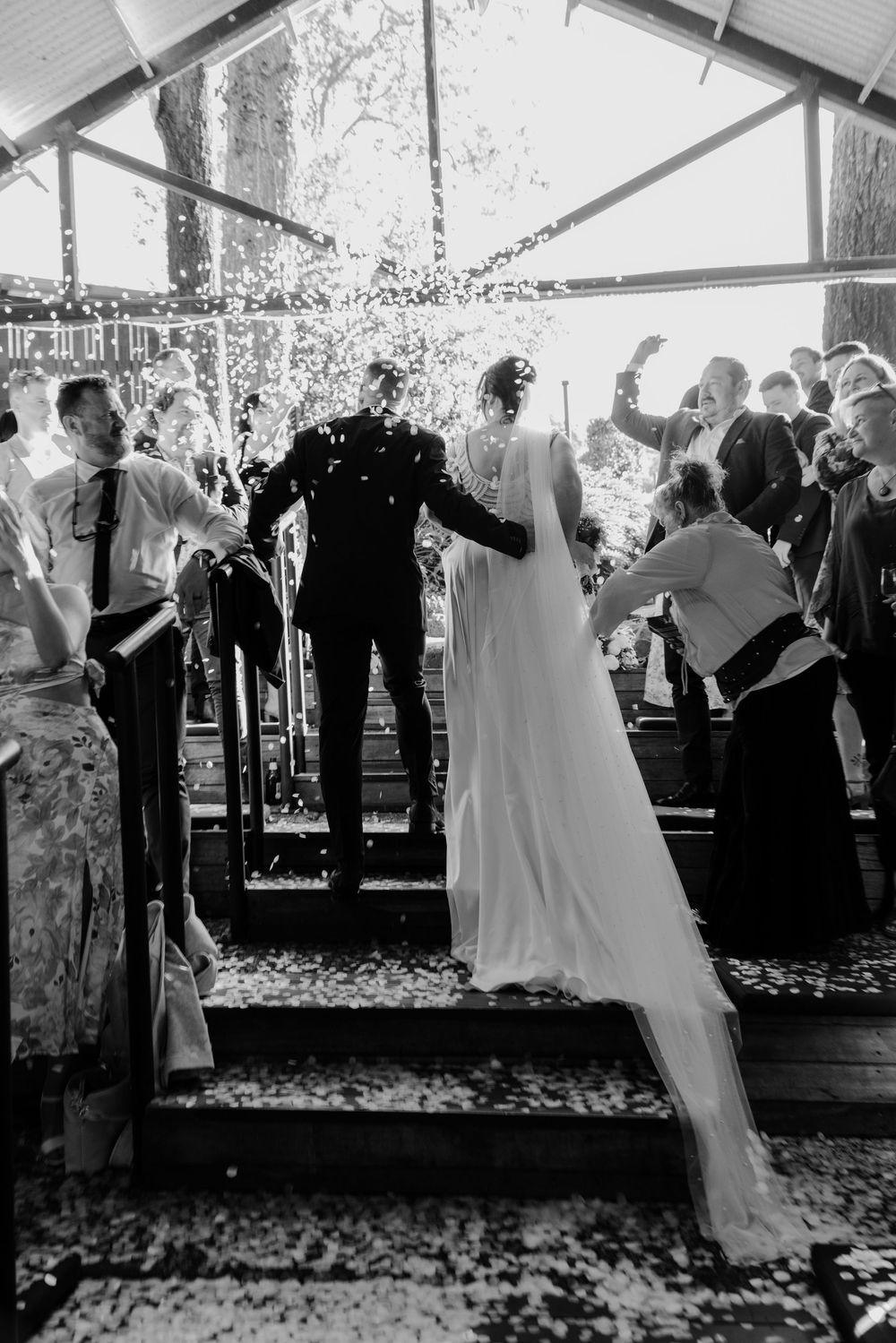 Black and white photo of wedding celebration with confetti falling inside tent reception.