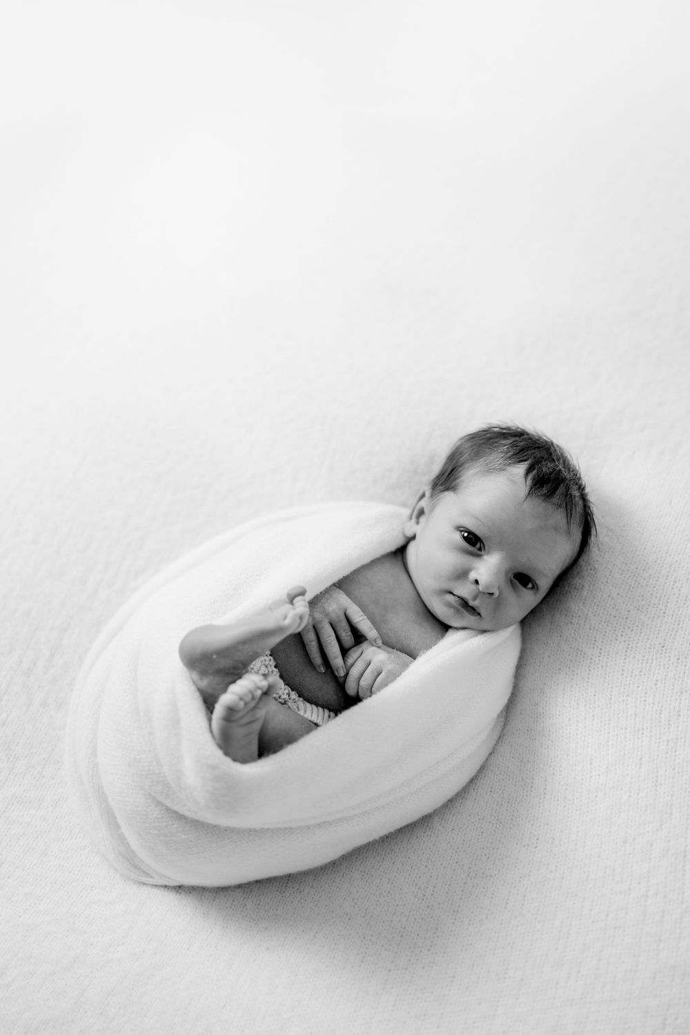 Black and white series of newborn baby sleeping in curved white bowl.