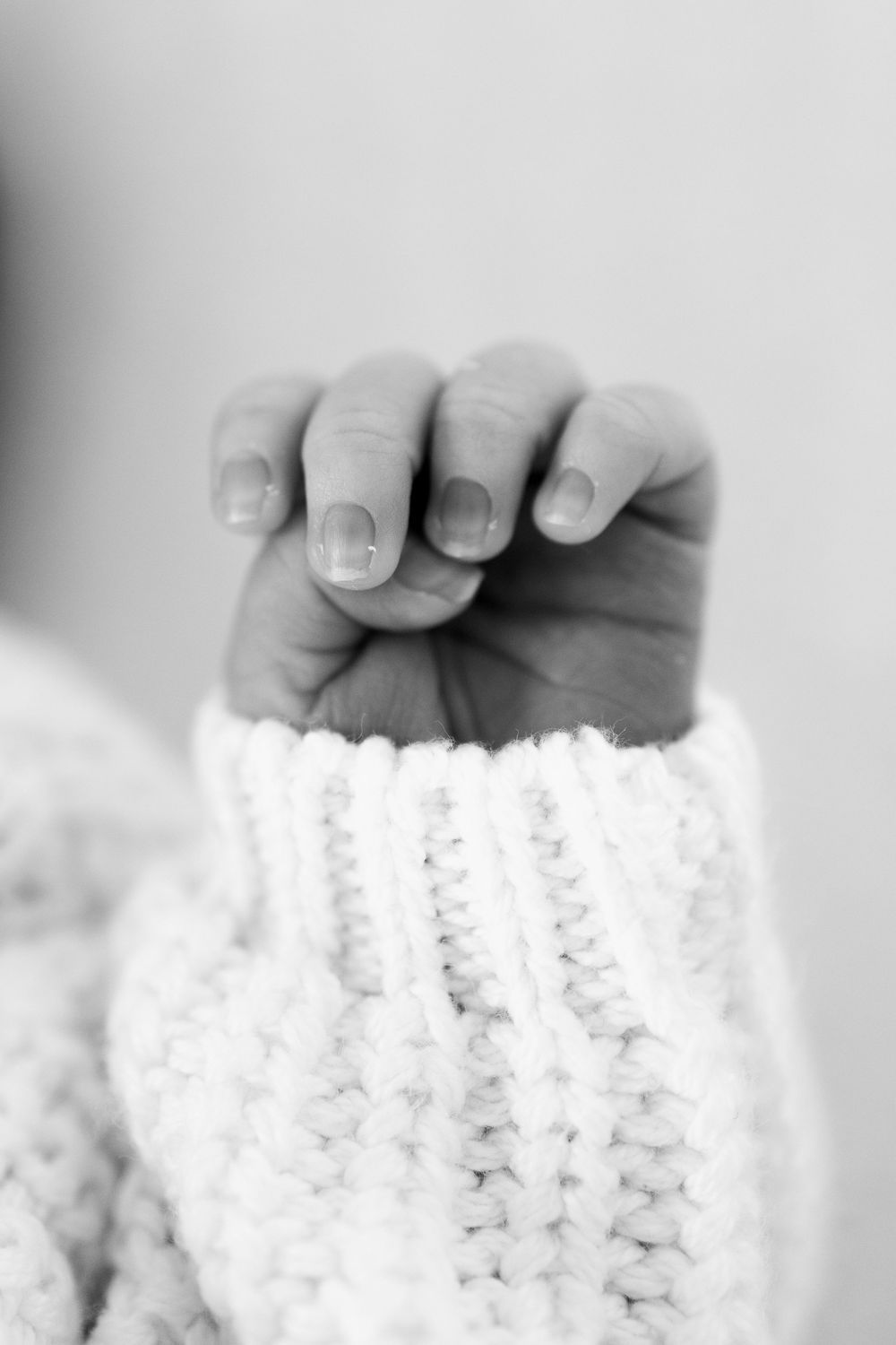 Detail shot of tiny baby feet resting on white knitted fabric.