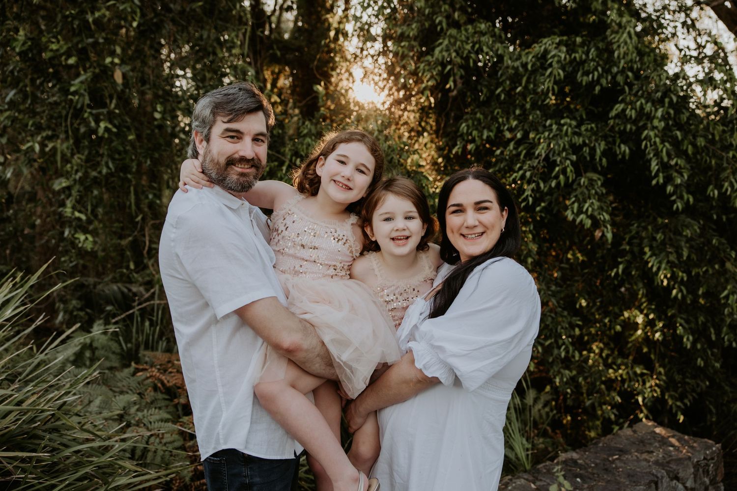 Family enjoying playful moments together in lush garden setting.