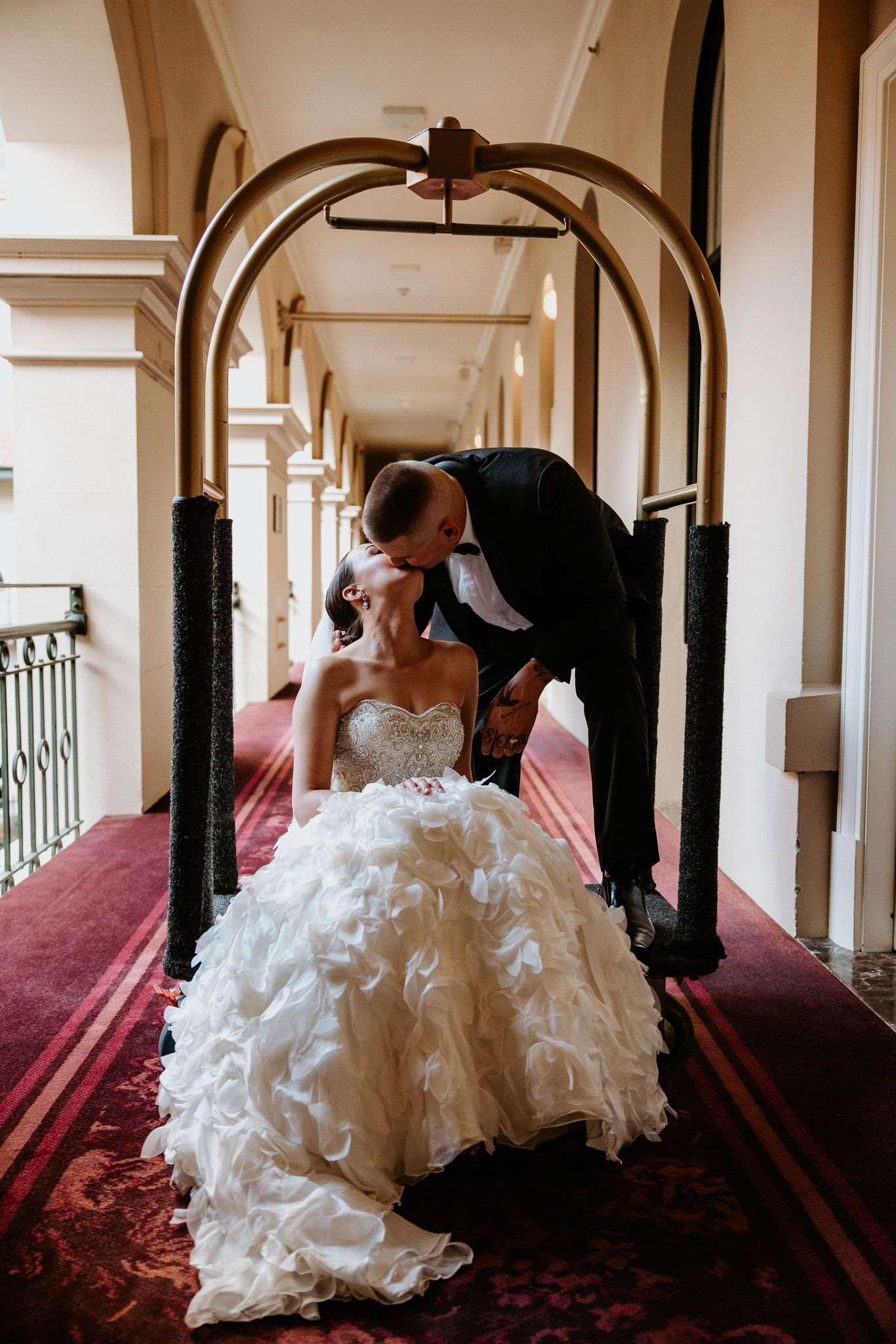 Romantic moment between couple under arched hallway with red carpet.