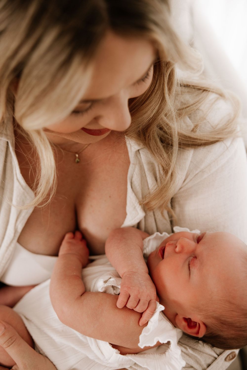 Tender maternal moments captured in soft white tones showing gentle nurturing.