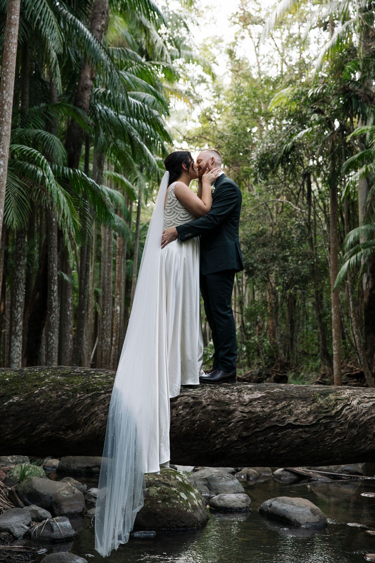 Romantic wedding portraits taken on rustic wooden bridge in tropical palm garden setting.