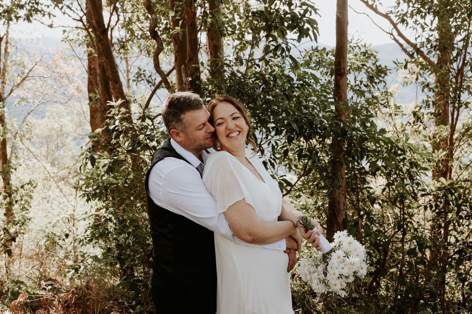 Natural light family portraits captured in a wooded setting with sunlight streaming through trees.